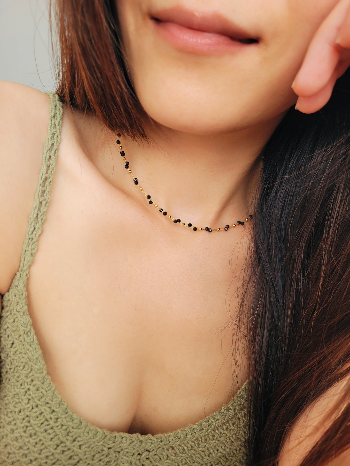 Close-up of a woman wearing a black spinel beaded choker necklace with 22k gold accents, styled for minimalist everyday wear. Handmade in natural gemstone and gold plated sterling silver premium materials, perfect gift for anniversary, birthday or self care.