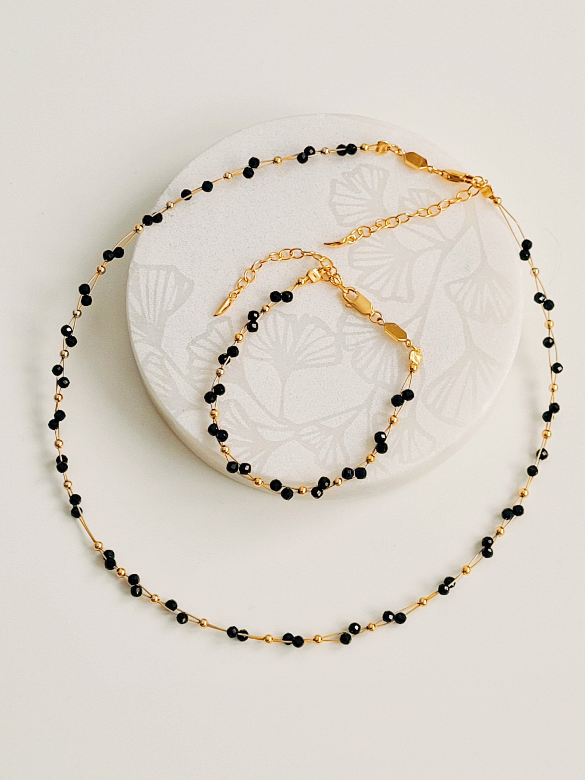 Close-up of a black spinel beaded choker necklace with 22k gold accents, styled for minimalist everyday wear. Handmade in natural gemstone and gold plated sterling silver premium materials, perfect gift for anniversary, birthday or self care.