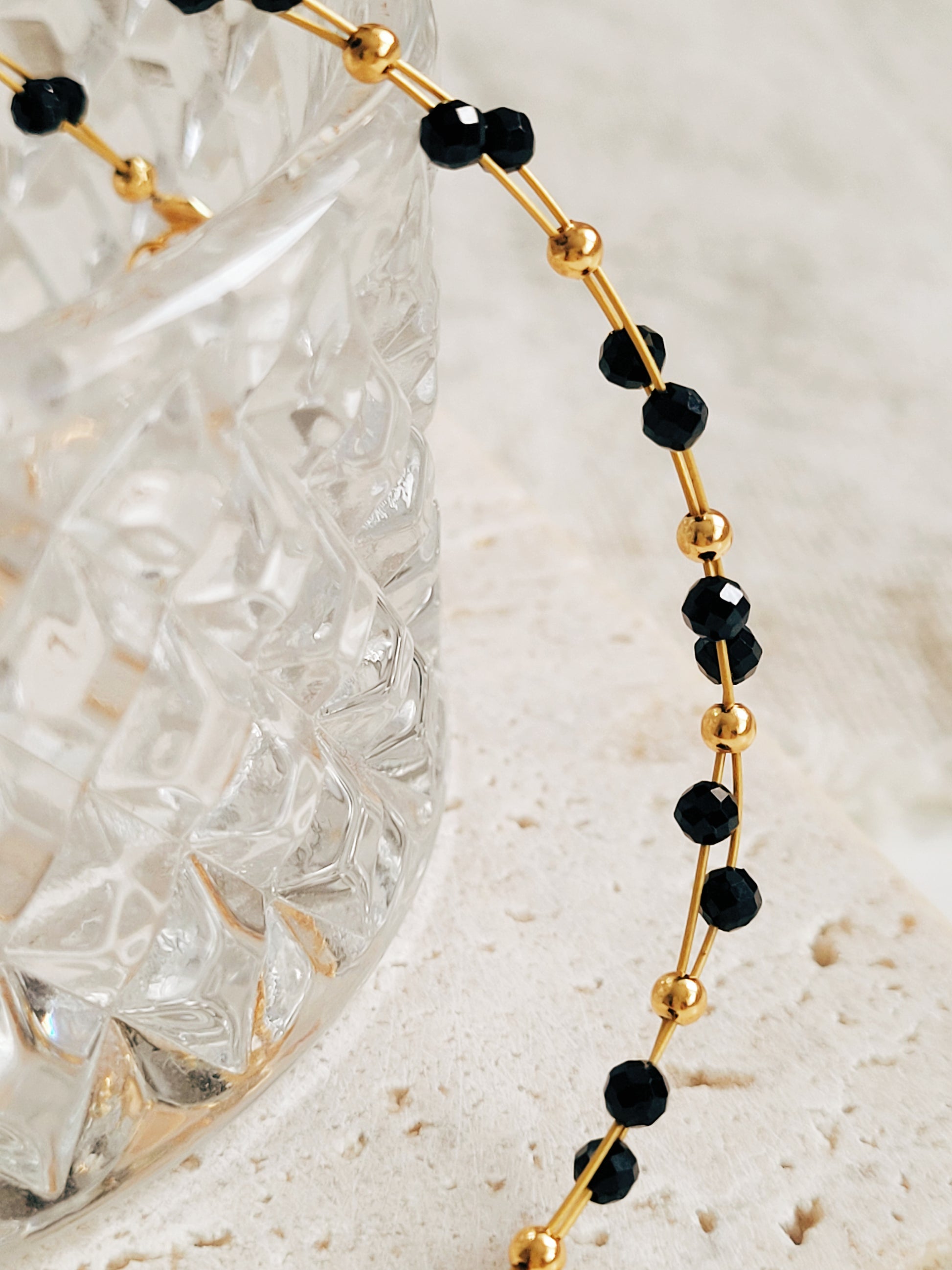 Close-up of a black spinel beaded bangle bracelet with 22k gold accents, styled for minimalist everyday wear. Handmade in natural gemstone and gold plated sterling silver premium materials, perfect gift for anniversary, birthday or self care.