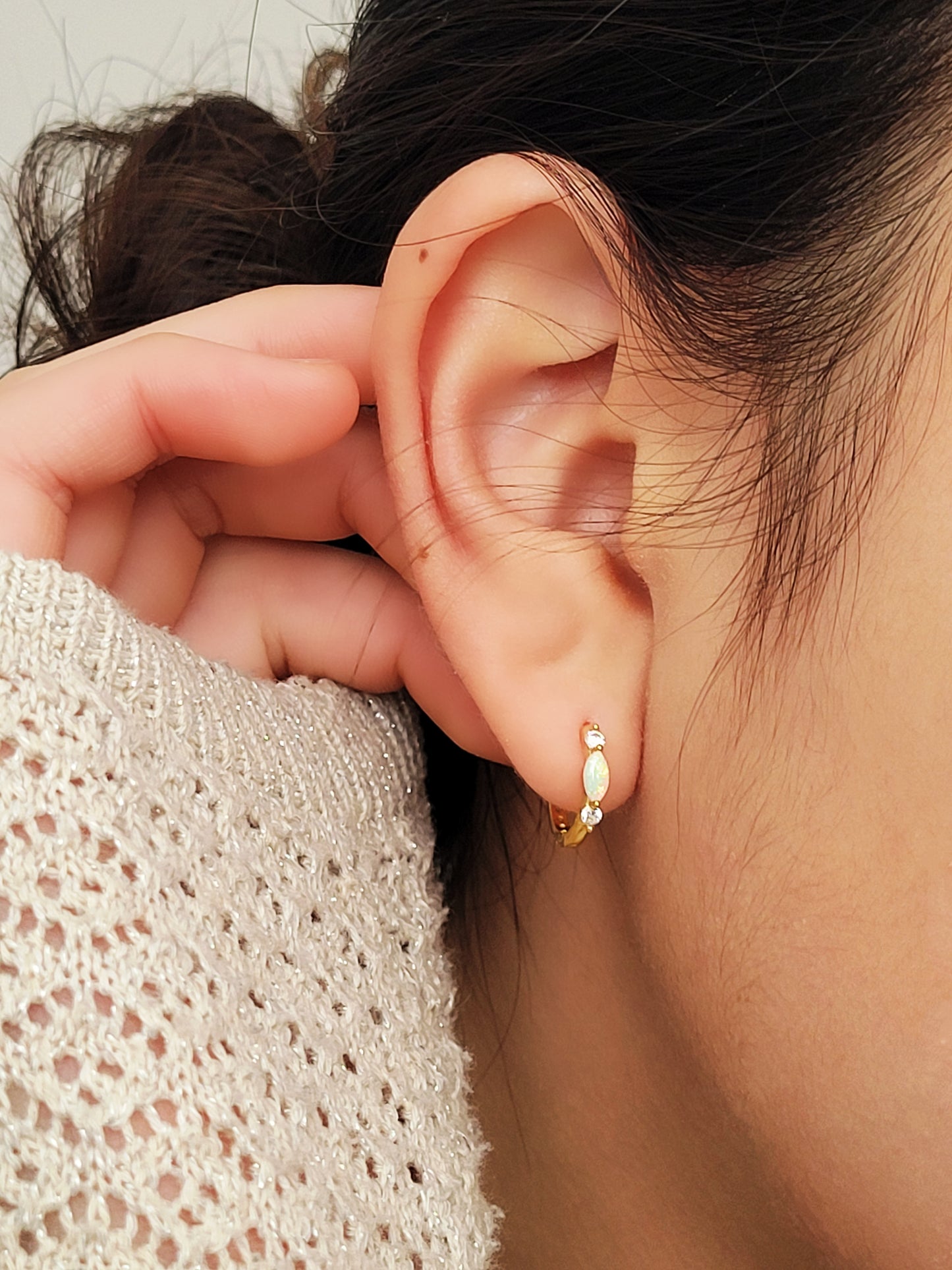 Close up of 18k gold plated sterling silver marquise opal huggie earrings, featuring a luminous opal accented with sparkling cubic zirconia.
