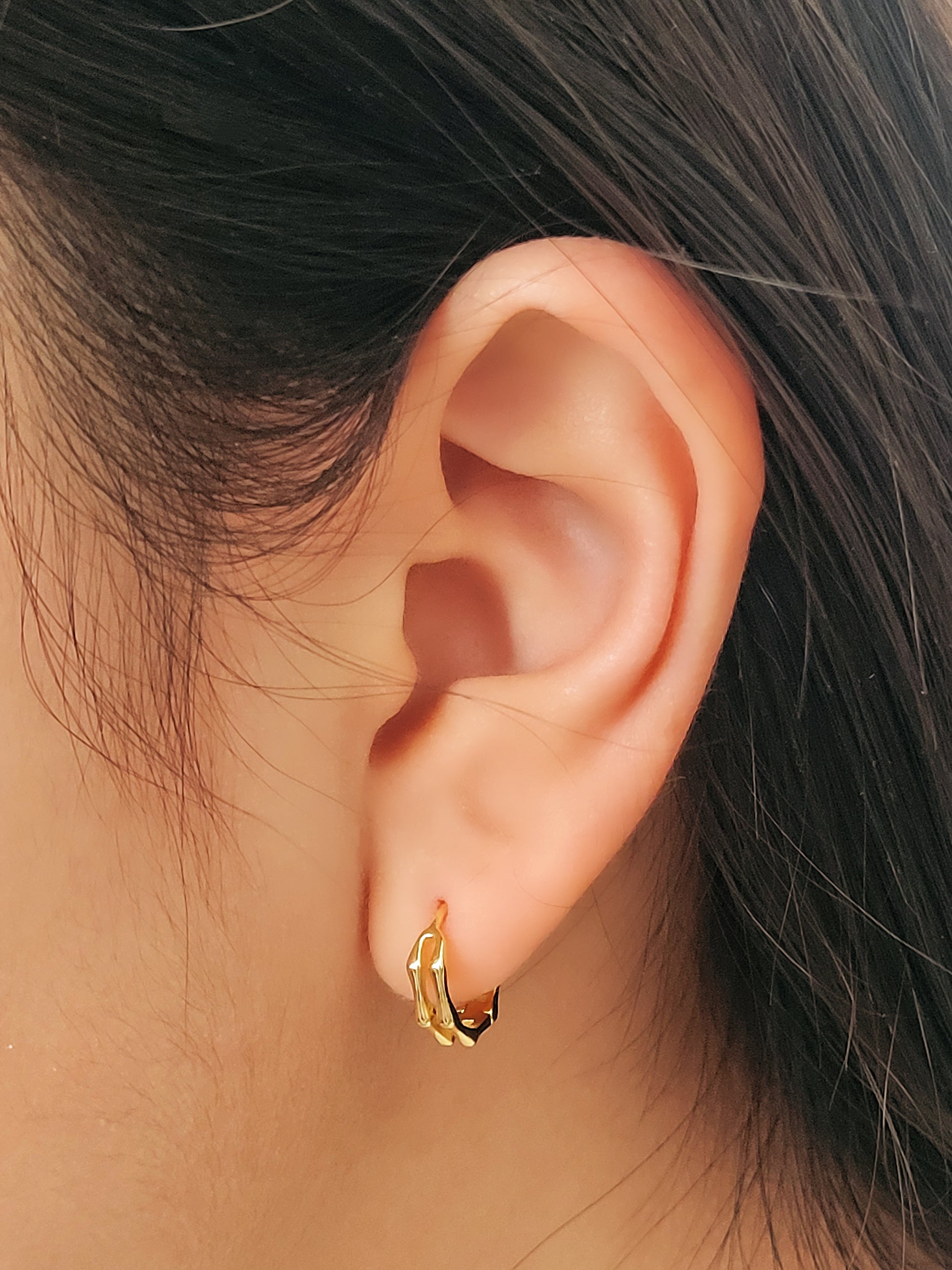 Close-up image of double hoop huggie earrings in octagon shape, featuring a minimalist gold geometric design, worn on an ear. Perfect for everyday wear.