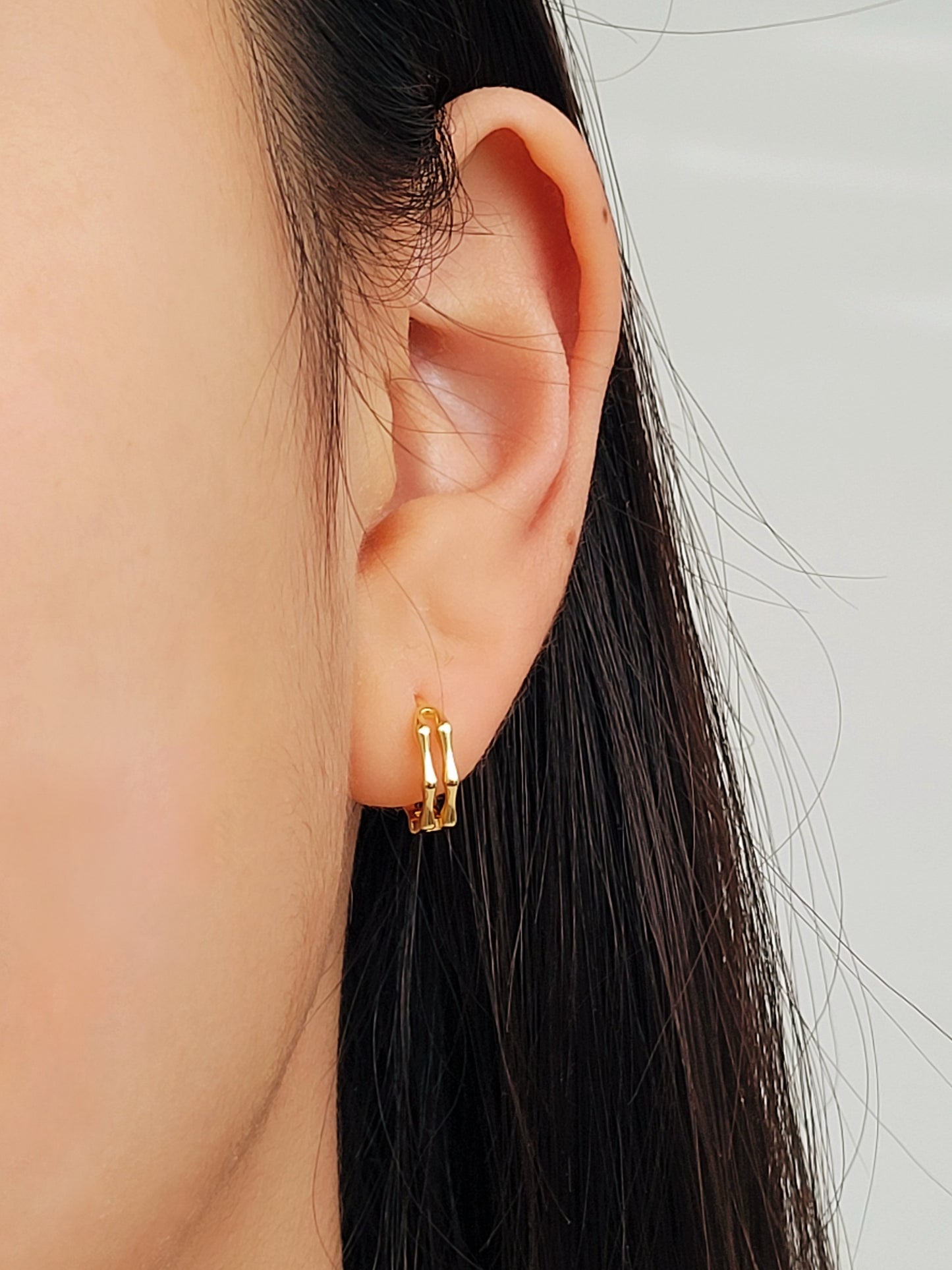 Close-up image of double hoop huggie earrings in octagon shape, featuring a minimalist gold geometric design, worn on an ear. Perfect for everyday wear.