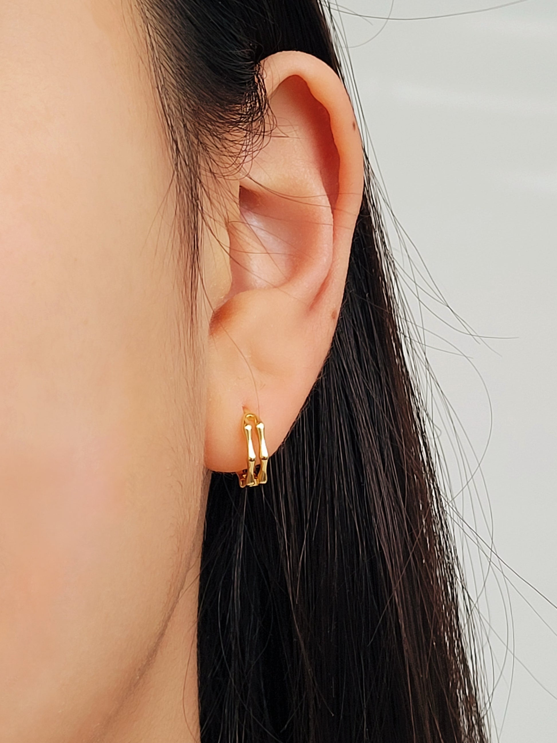 Close-up image of double hoop huggie earrings in octagon shape, featuring a minimalist gold geometric design, worn on an ear. Perfect for everyday wear.