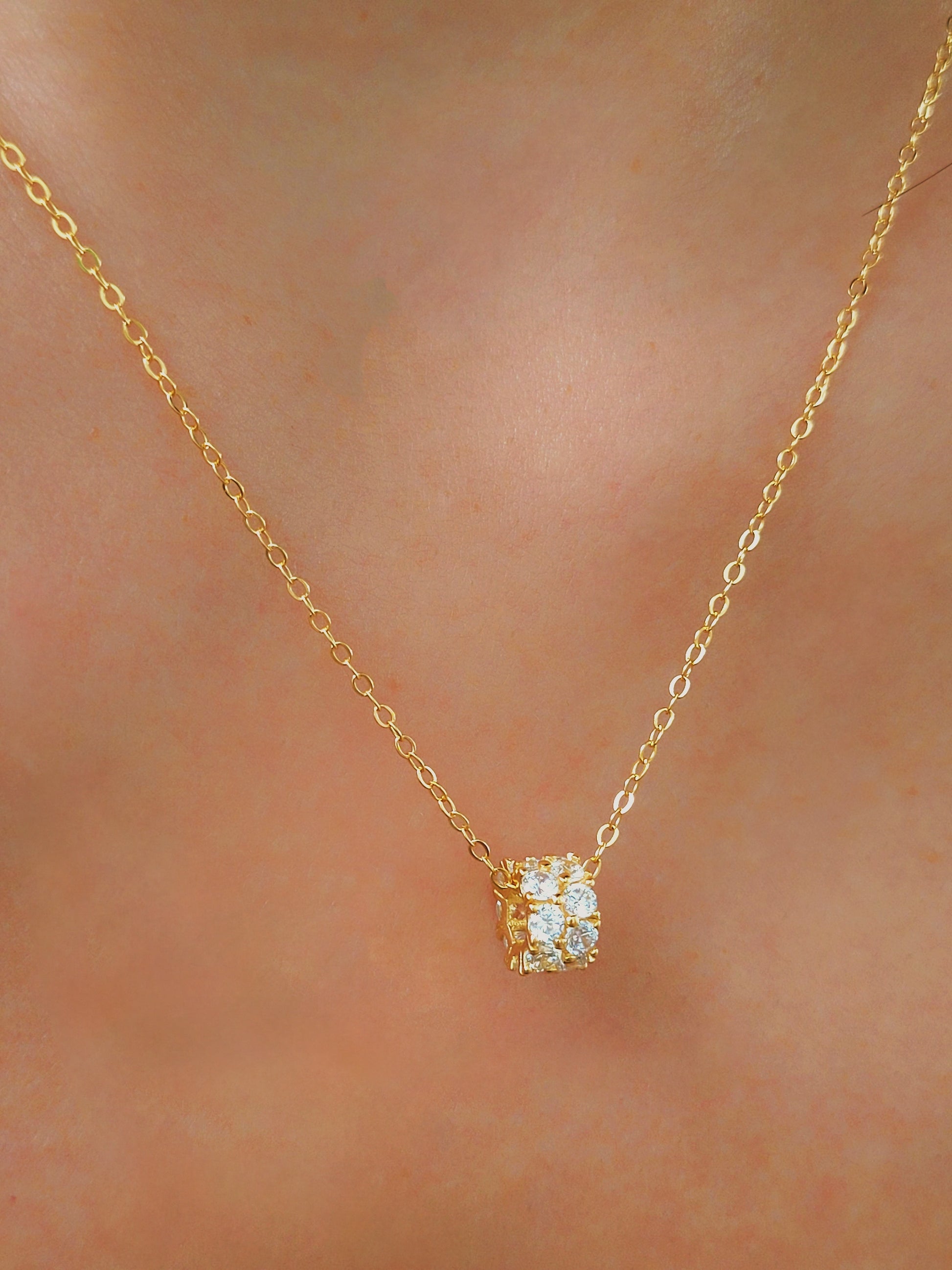 Luxurious close-up of a gold round shaped barrel necklace featuring sparkling pave zircons.