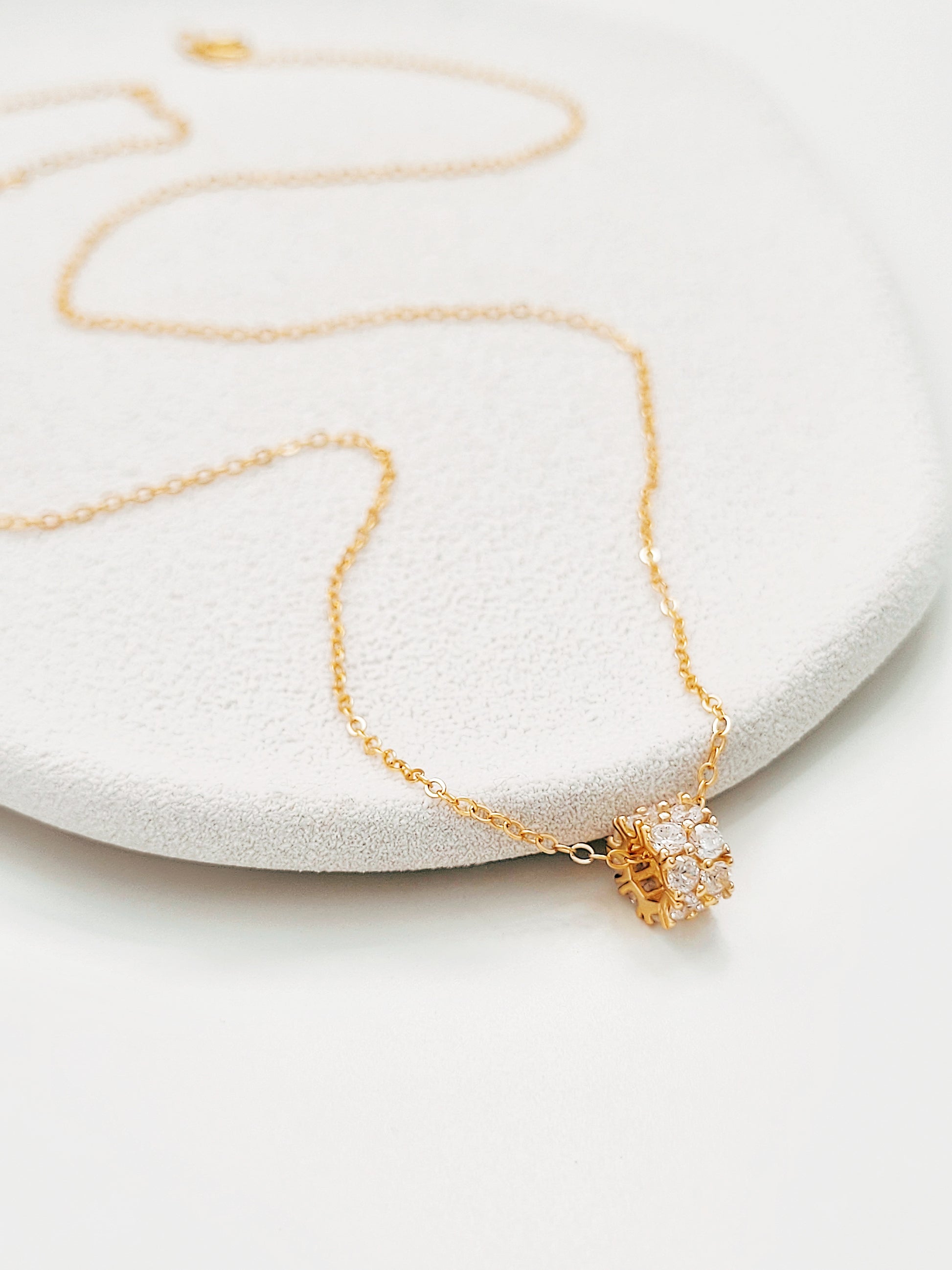 Luxurious close-up of a gold round shaped barrel necklace featuring sparkling pave zircons.