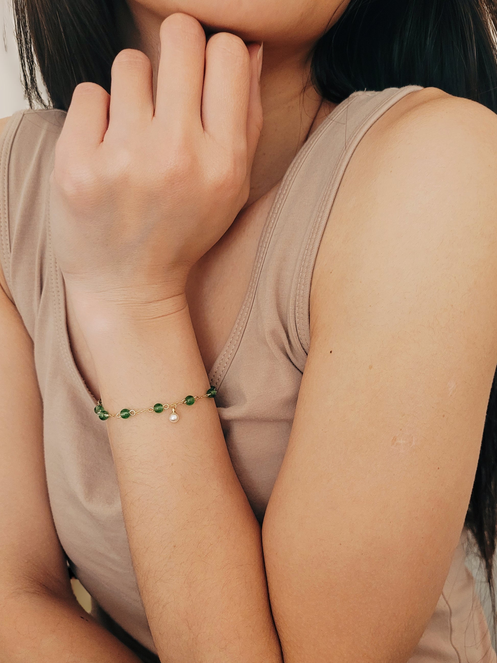 Elegant gold chain bracelet with green gemstone beads and a dainty pearl drop, perfect for a minimalist look.