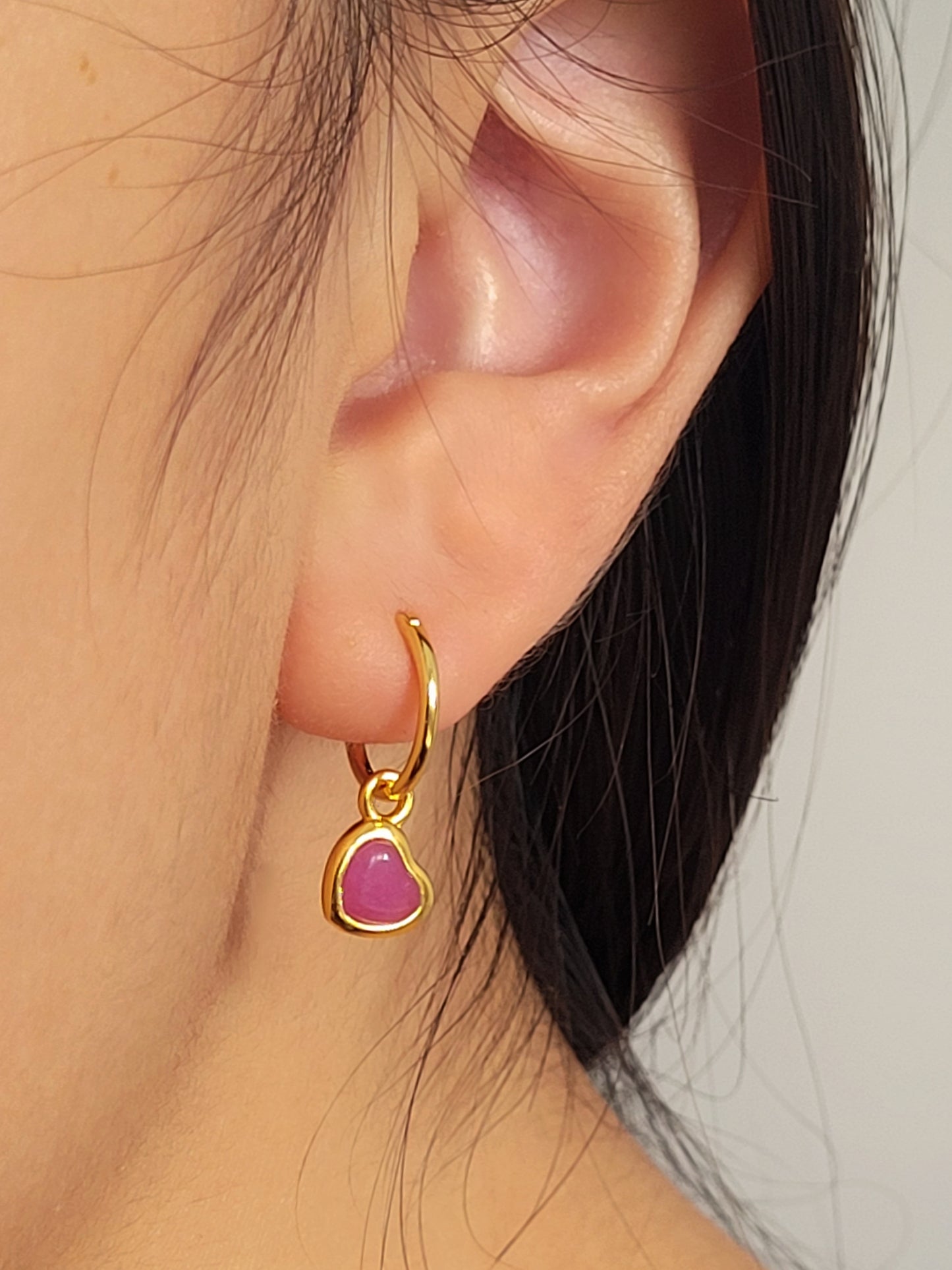 Gold earring with a pink heart crystal quartz worn by a woman