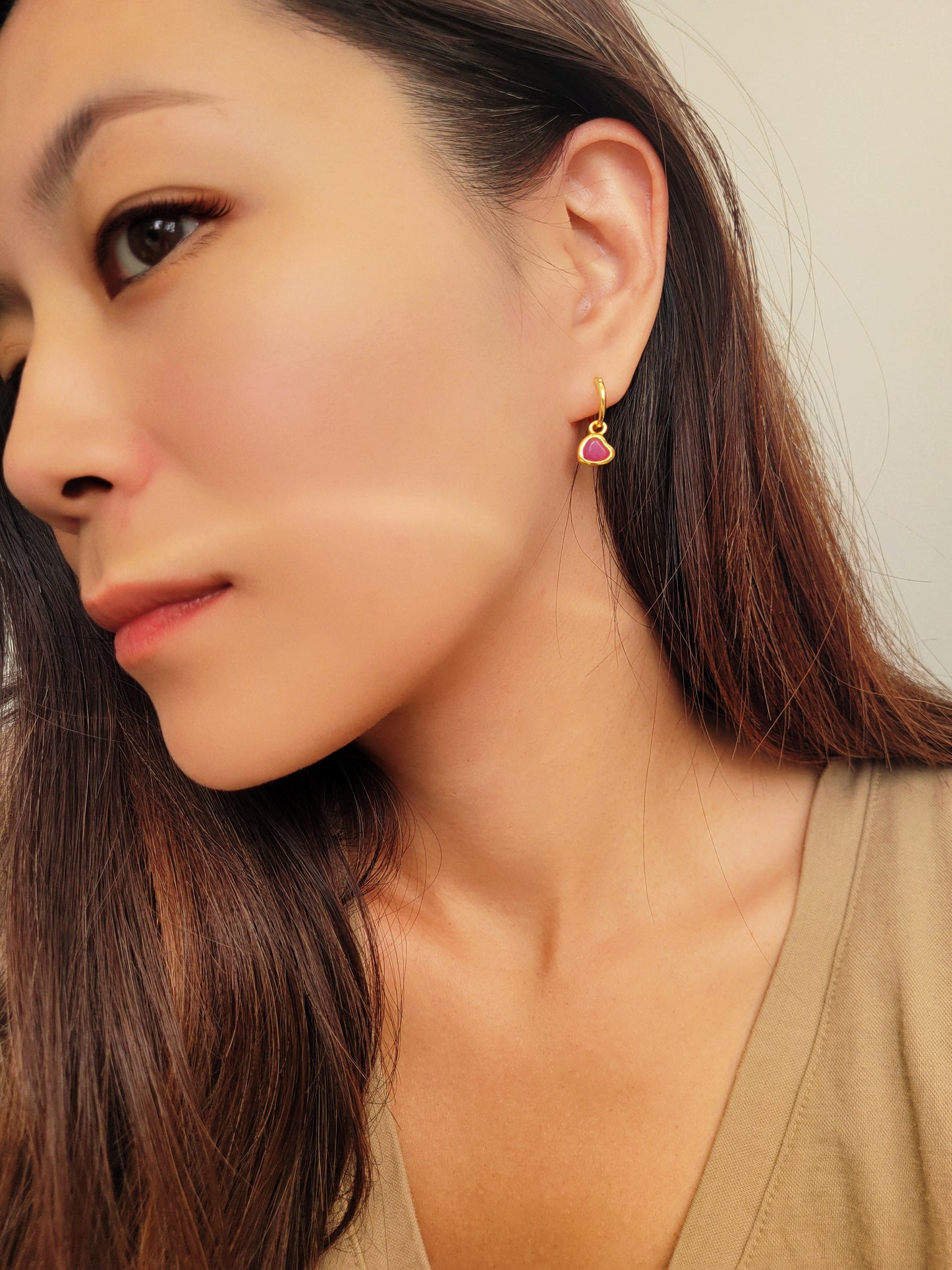 Woman wearing a pink heart gold hoop earrings, dainty and minimalist
