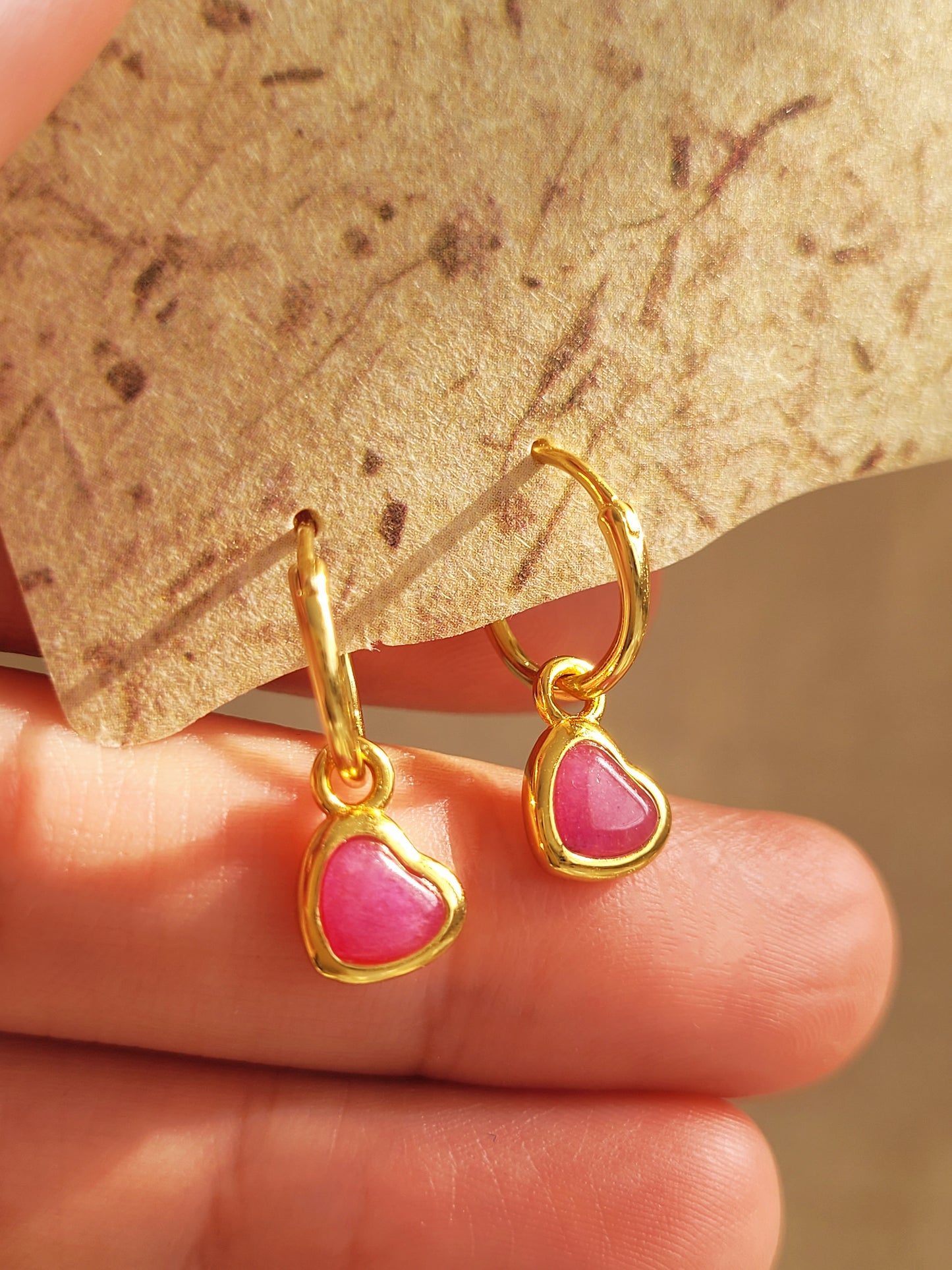 Close up of a pair of pink heart earrings, showcasing its details and beauty of natural gemstone