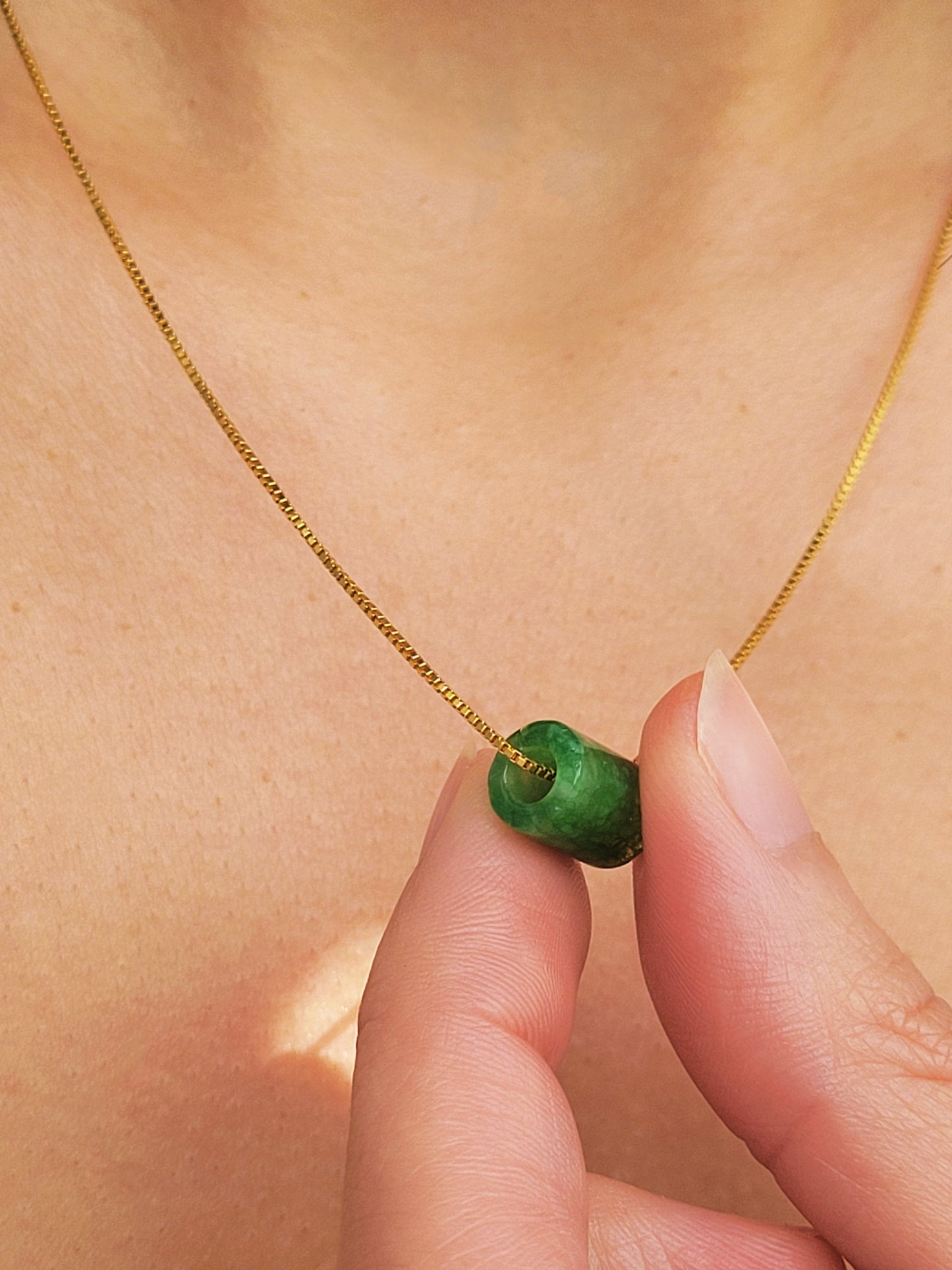 A natural green jade bead necklace with a polished finish, strung on a gold-plated sterling silver chain, offering a minimalist and elegant style.