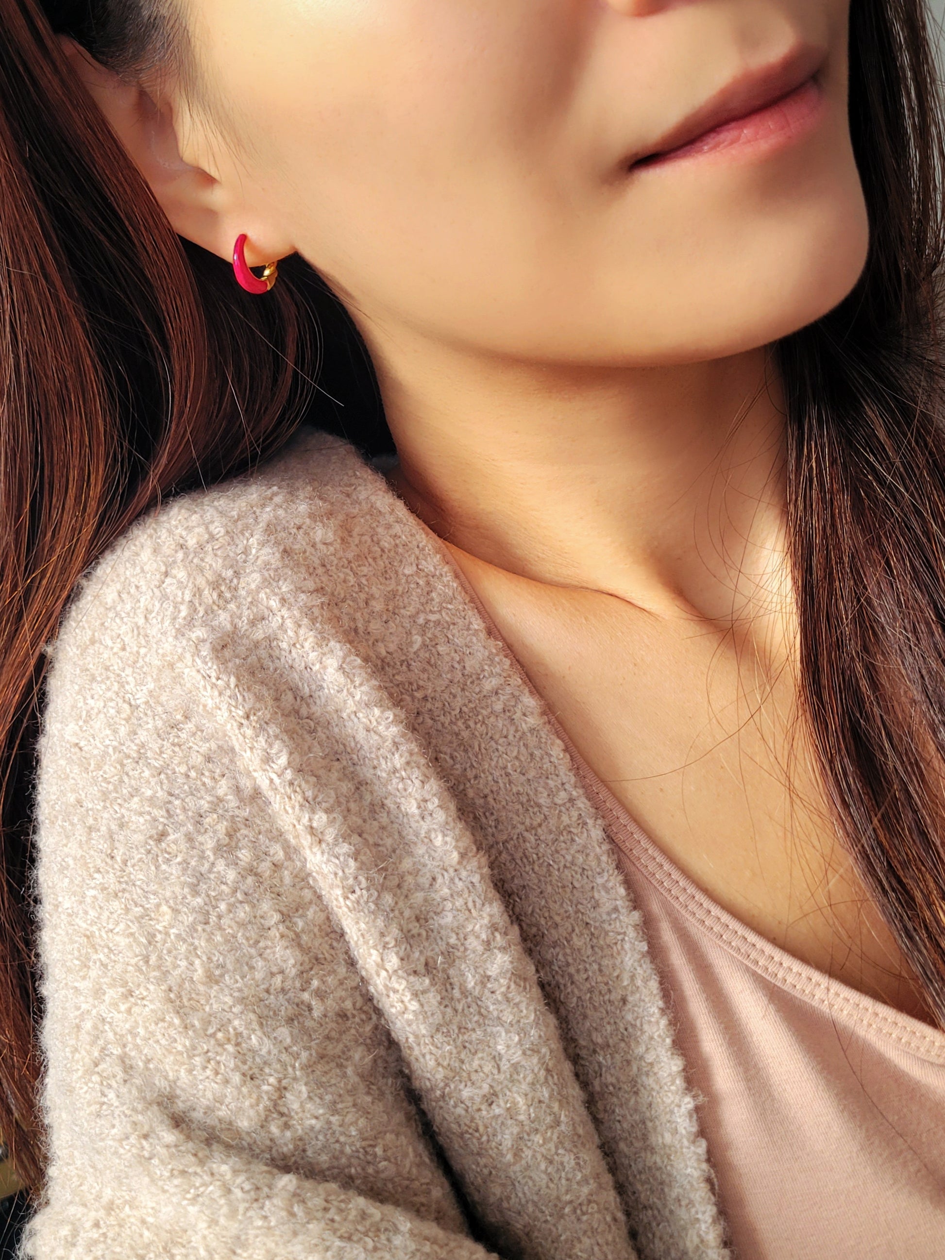 Close-up view of pink and gold enamel hoop earrings featuring twisted gold detail and vibrant green enamel finish.