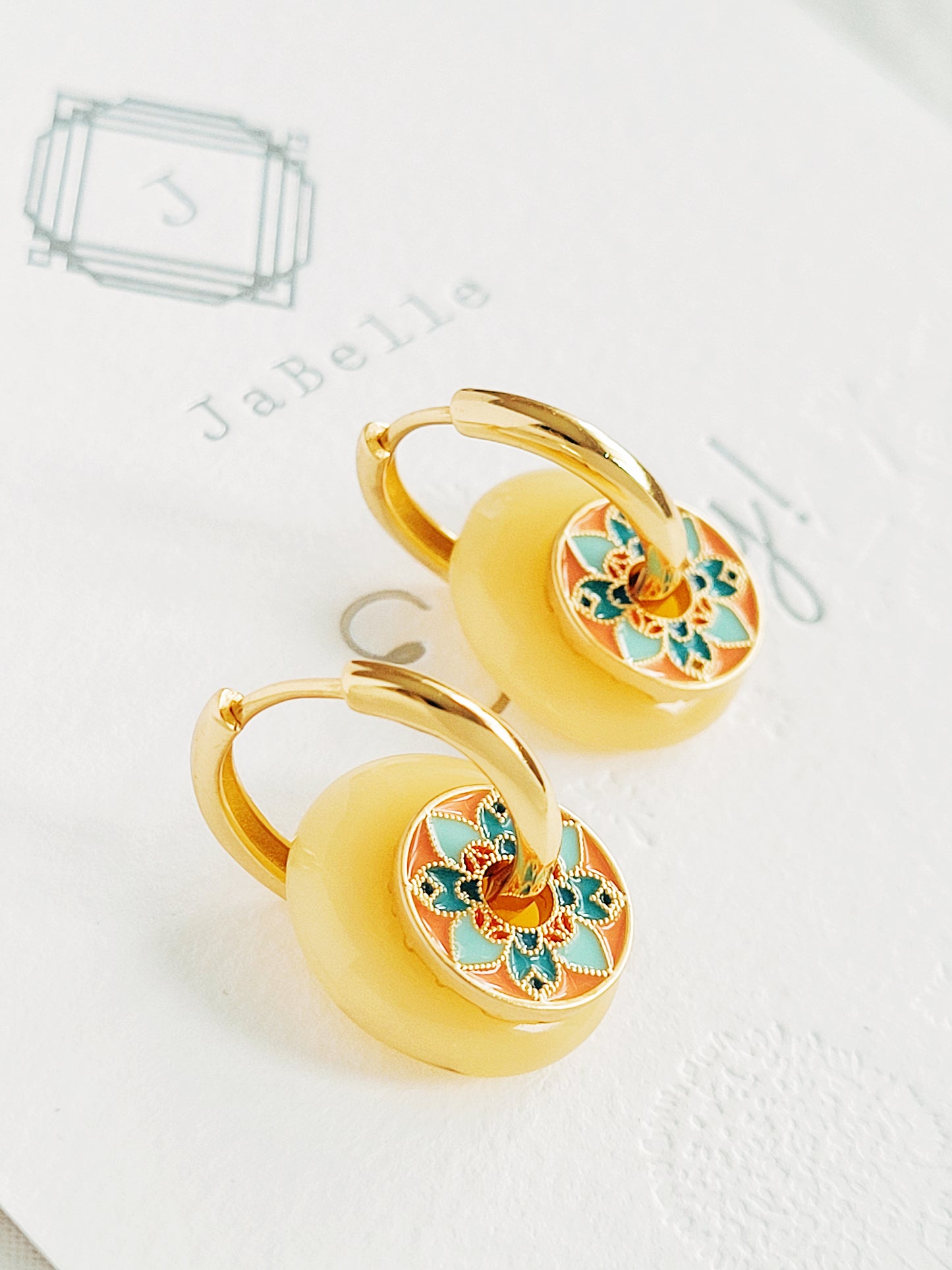 Close-up of vintage tile-pattern-inspired gold hoop earrings with floral detailing, displayed on a white background.