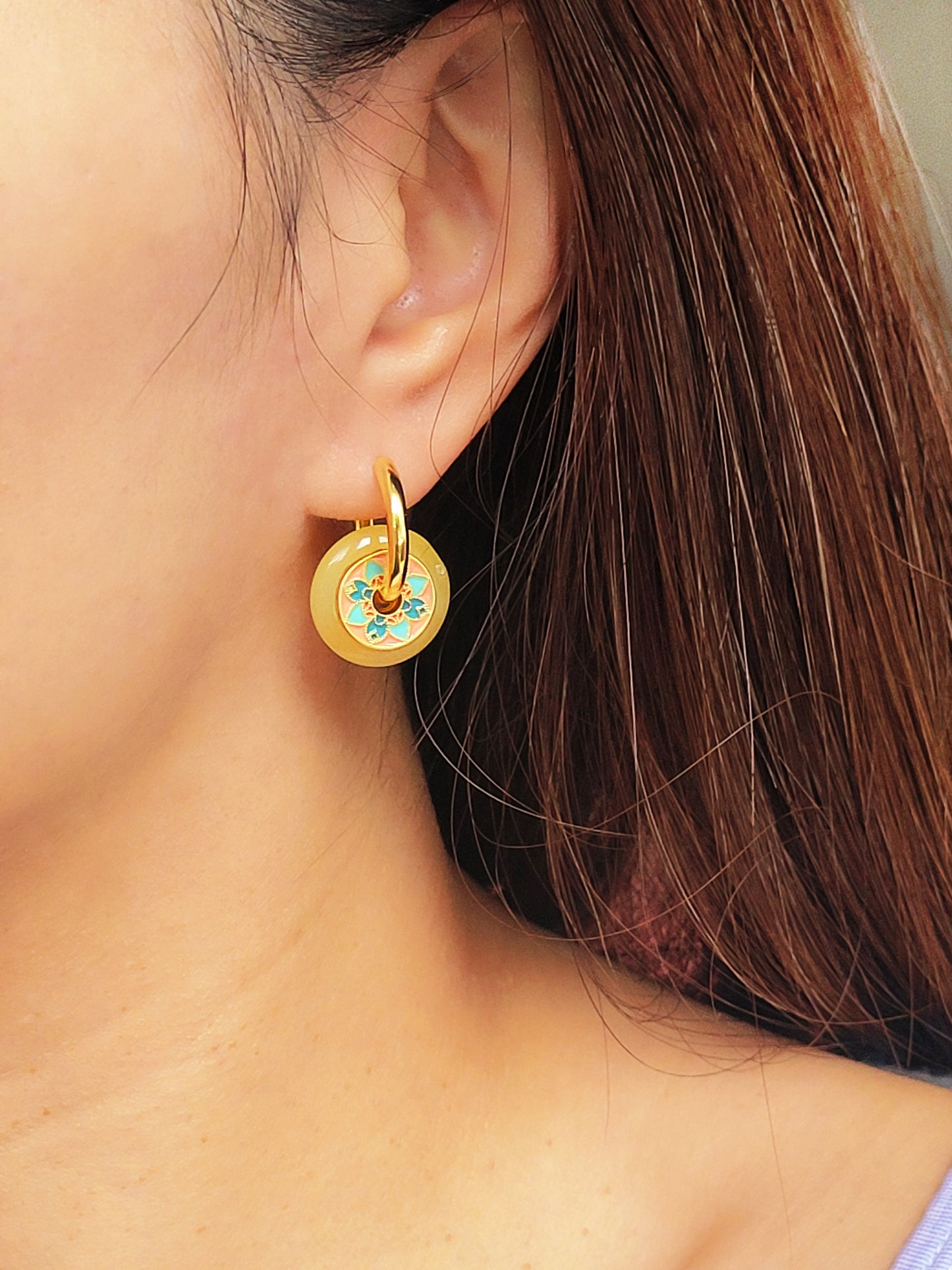 Close-up of a woman wearing vintage tile pattern inspired gold hoop earrings with floral detailing.