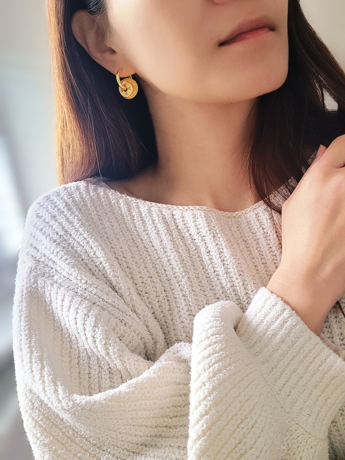 Close-up of a woman wearing vintage tile pattern inspired gold hoop earrings with floral detailing.