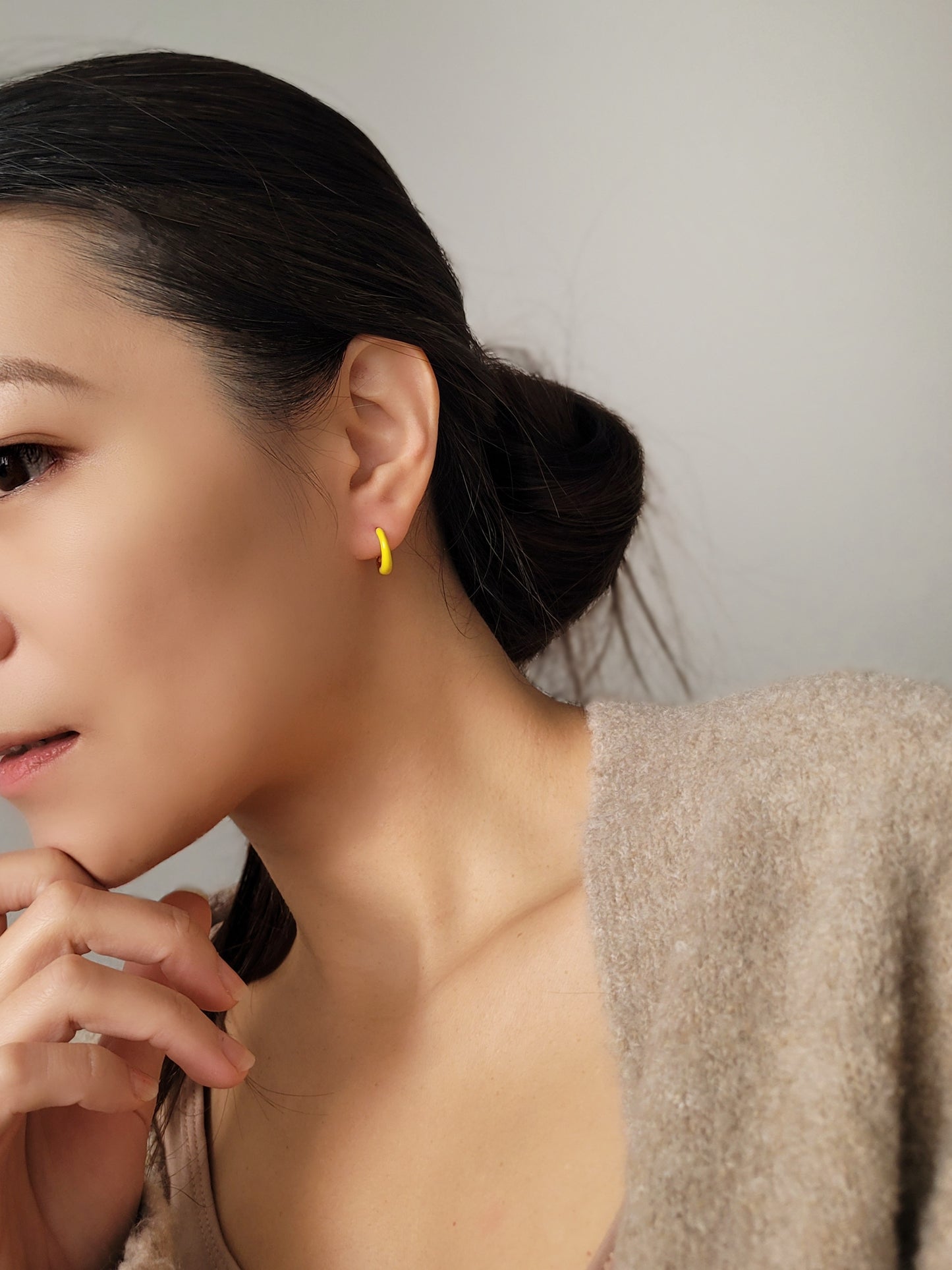 Model wearing small yellow and gold enamel hoop earrings, showcasing their elegant and lightweight design.
