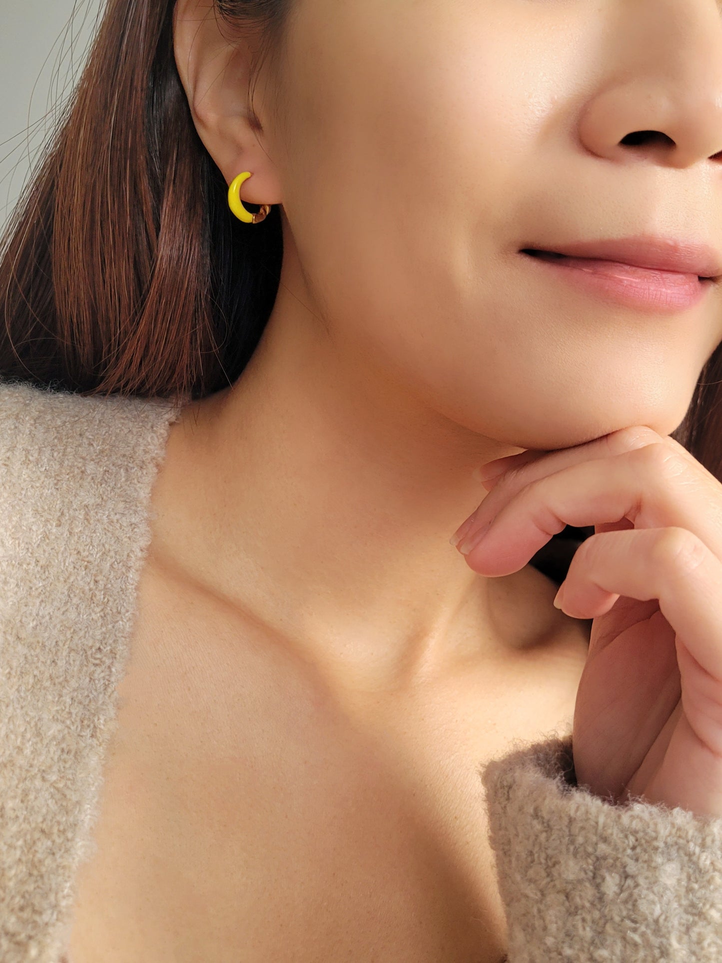Model wearing small yellow and gold enamel hoop earrings, showcasing their elegant and lightweight design.