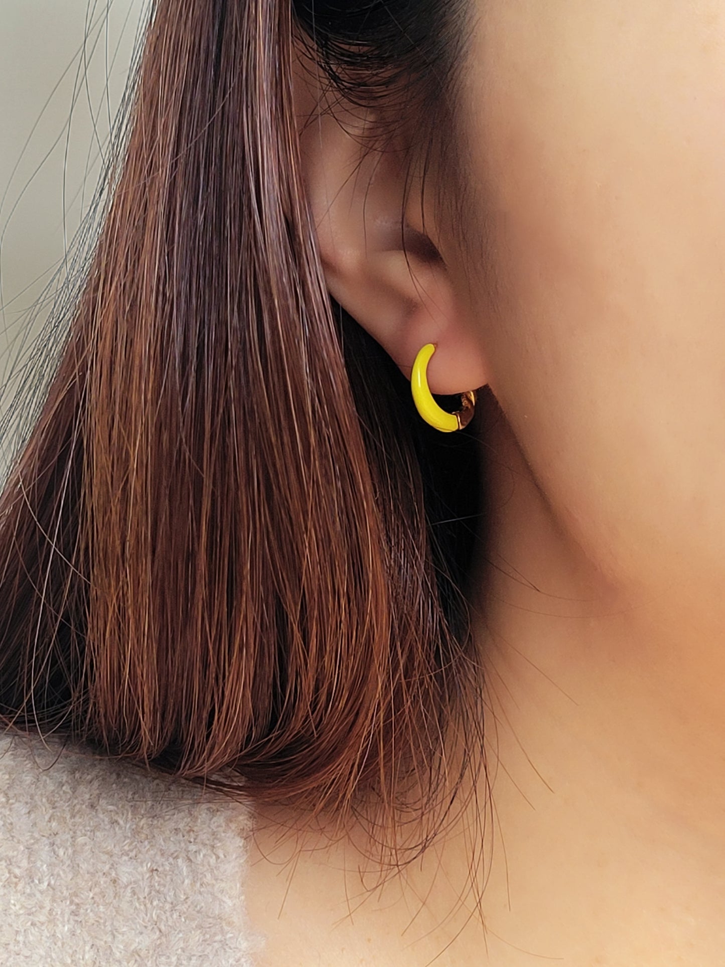 Model wearing small yellow and gold enamel hoop earrings, showcasing their elegant and lightweight design.