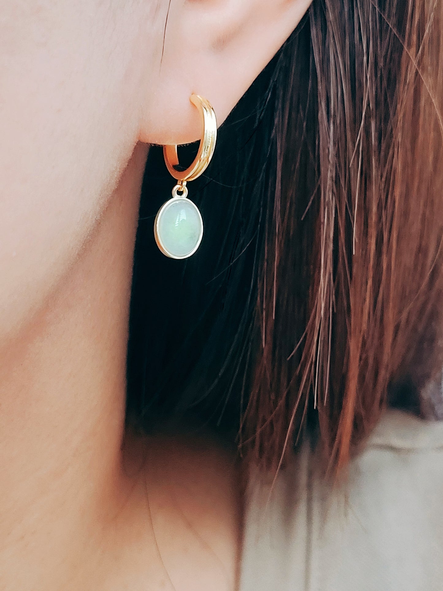A woman adorned with a green aventurine drop earrings, showcasing natural gemstone elegance.
