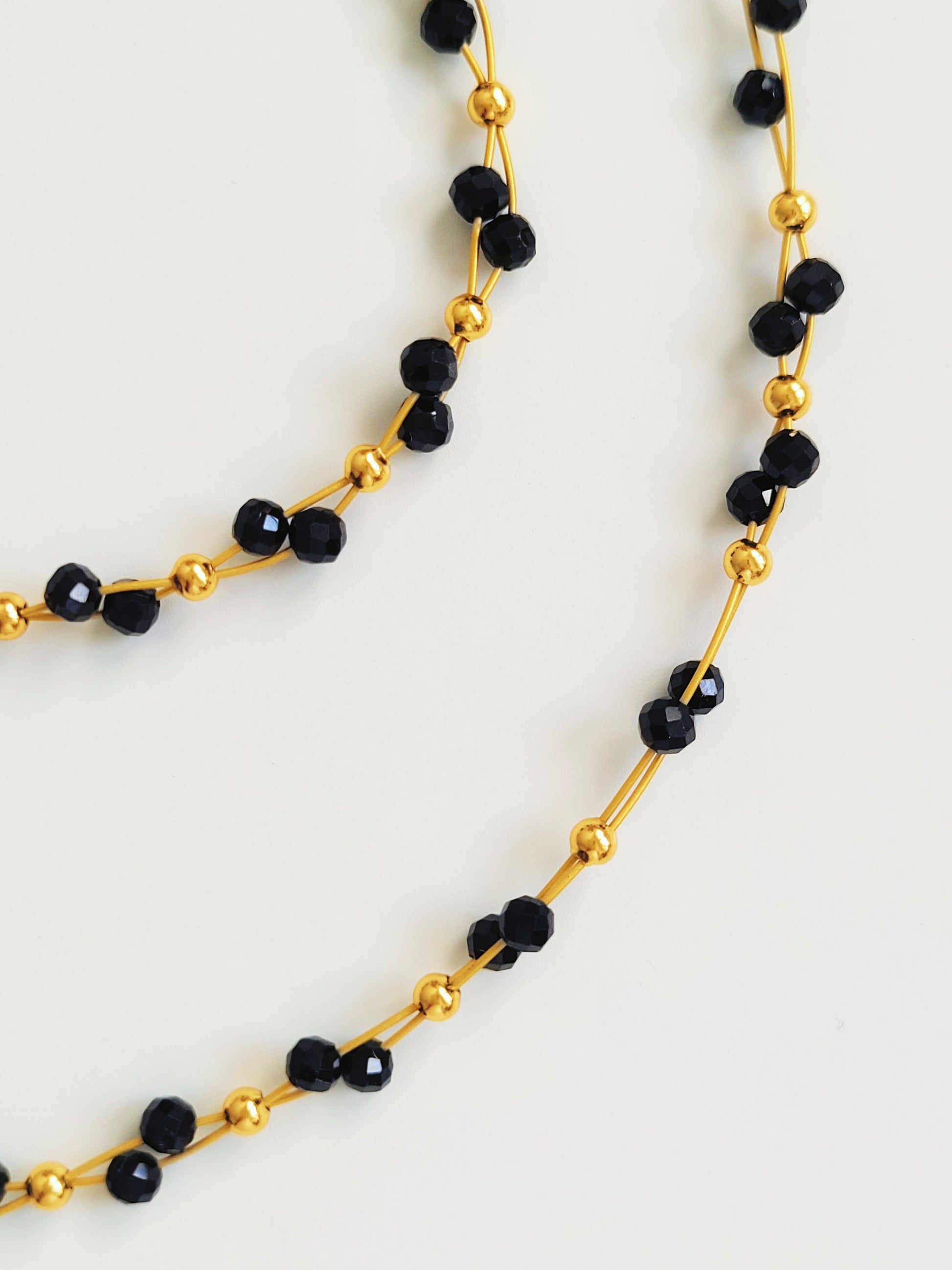 Close-up of a black spinel beaded bangle bracelet and necklace set with 22k gold accents, styled for minimalist everyday wear. Handmade in natural gemstone and gold plated sterling silver premium materials, perfect gift for anniversary, birthday or self care.