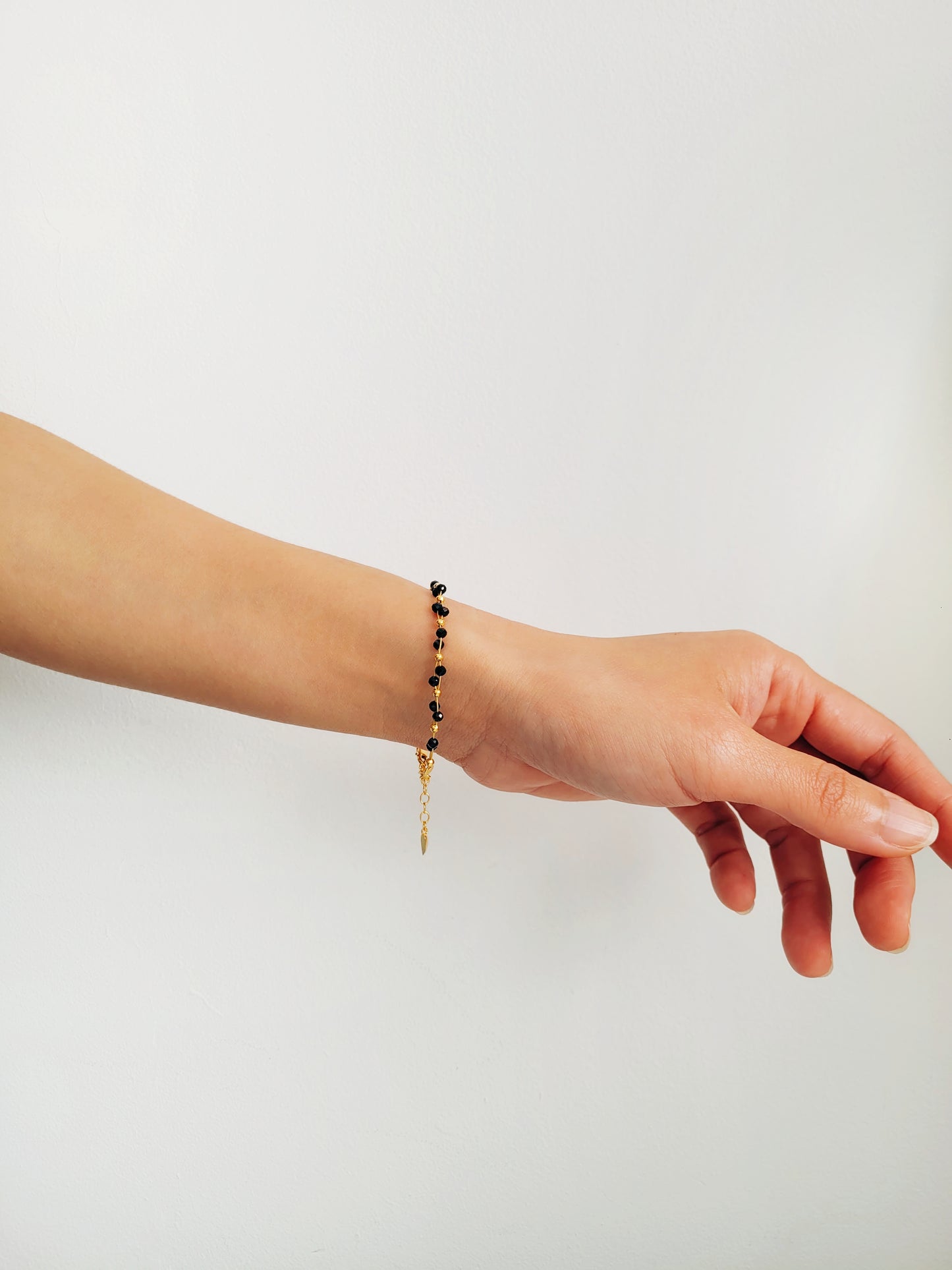 Close-up of a black spinel beaded bangle bracelet with 22k gold accents, styled for minimalist everyday wear. Handmade in natural gemstone and gold plated sterling silver premium materials, perfect gift for anniversary, birthday or self care.
