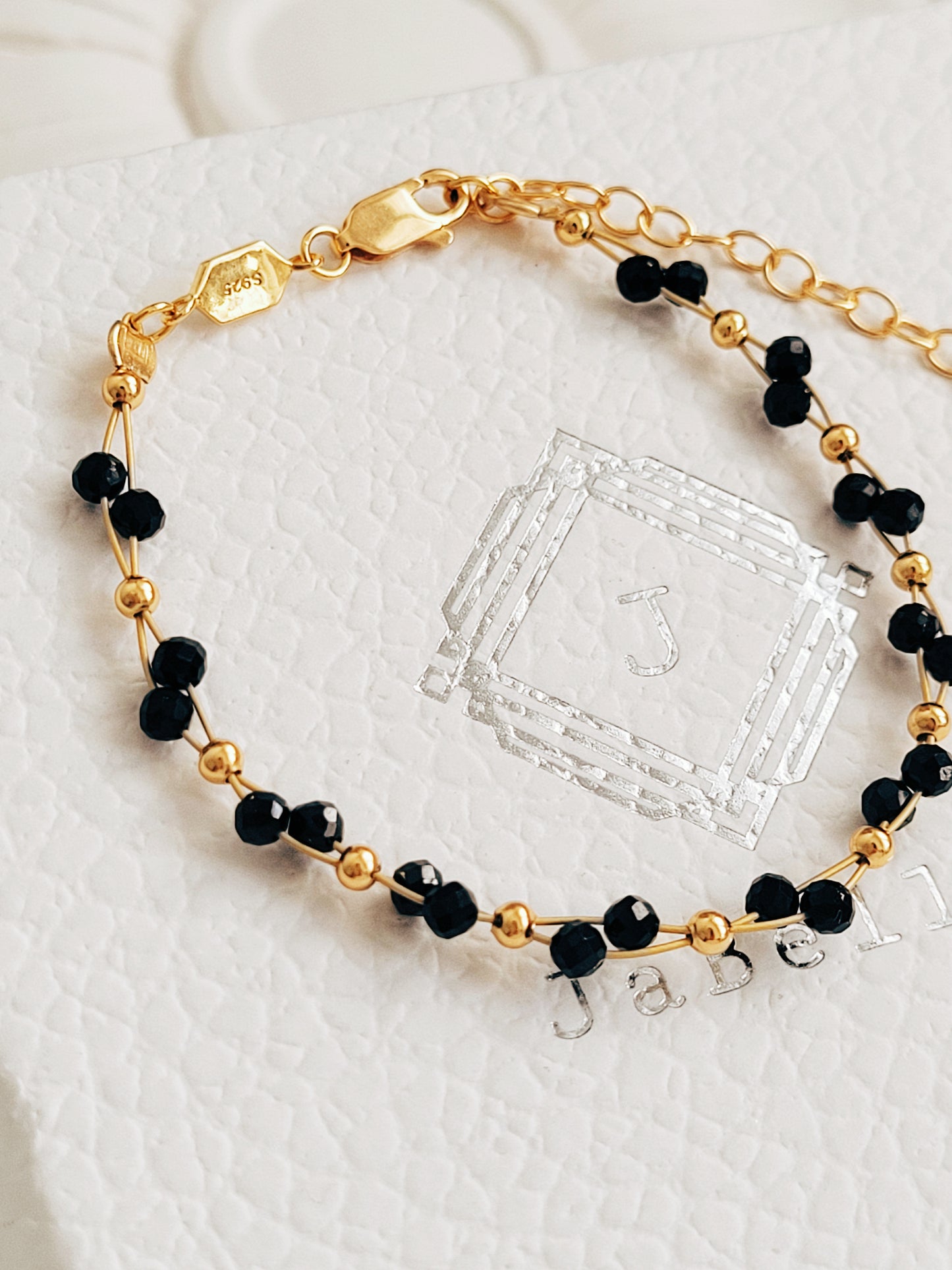 Close-up of a black spinel beaded bangle bracelet with 22k gold accents, styled for minimalist everyday wear. Handmade in natural gemstone and gold plated sterling silver premium materials, perfect gift for anniversary, birthday or self care.