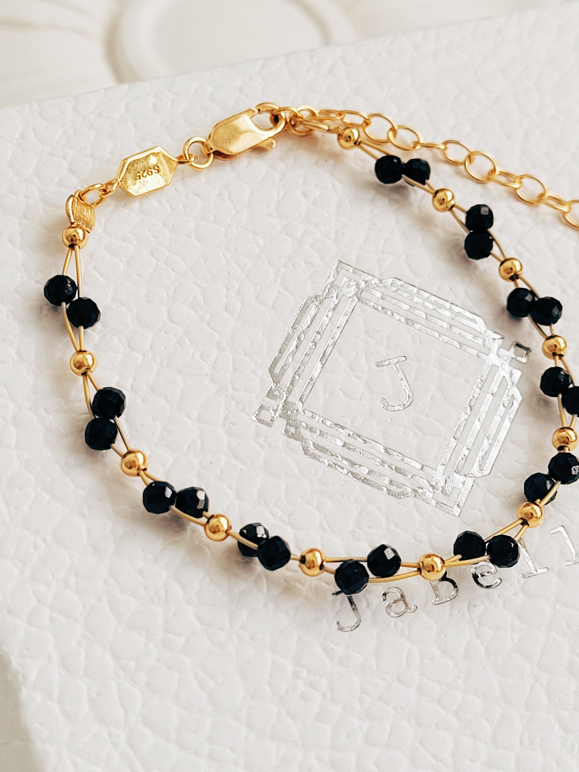 Close-up of a black spinel beaded bangle bracelet with 22k gold accents, styled for minimalist everyday wear. Handmade in natural gemstone and gold plated sterling silver premium materials, perfect gift for anniversary, birthday or self care.