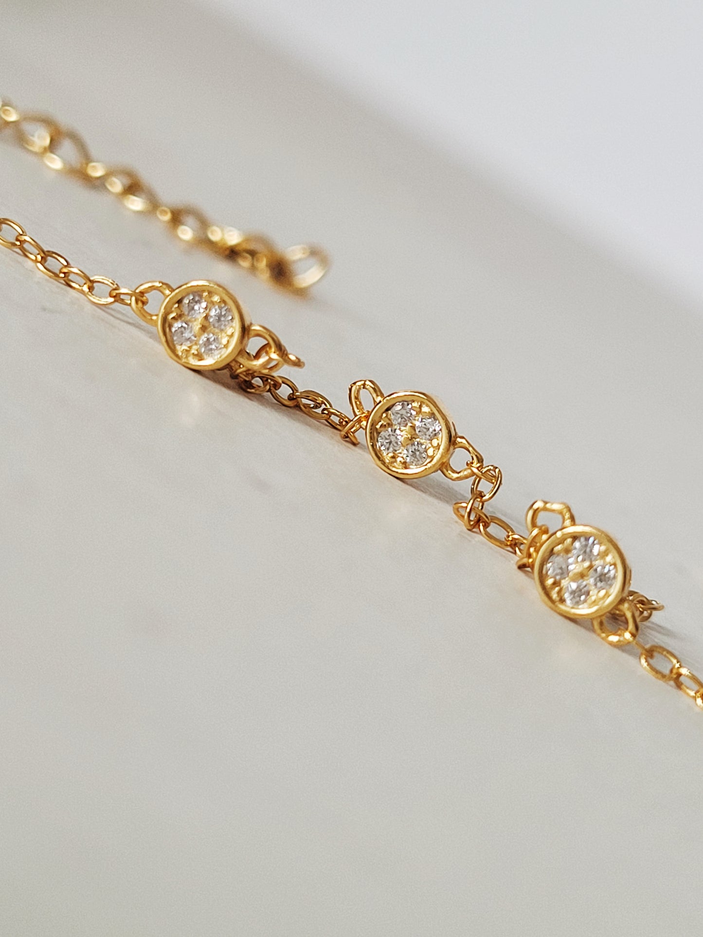 a gold chain featuring three small diamond style zicron circles, elegantly showcasing a blend of luxury and simplicity in its design.