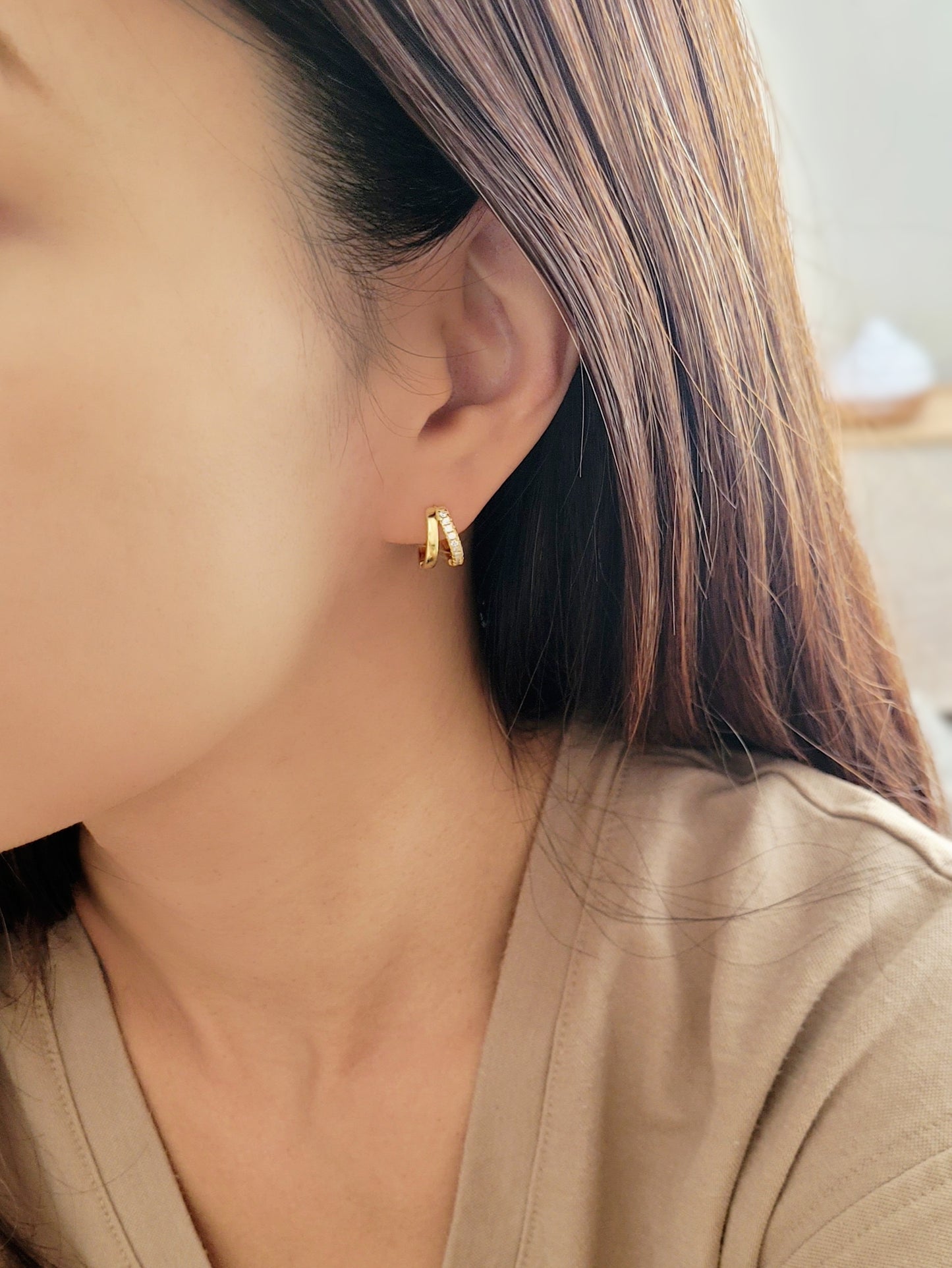 A woman adorned with beautiful gold double huggie hoop earrings, radiating elegance and sophistication.