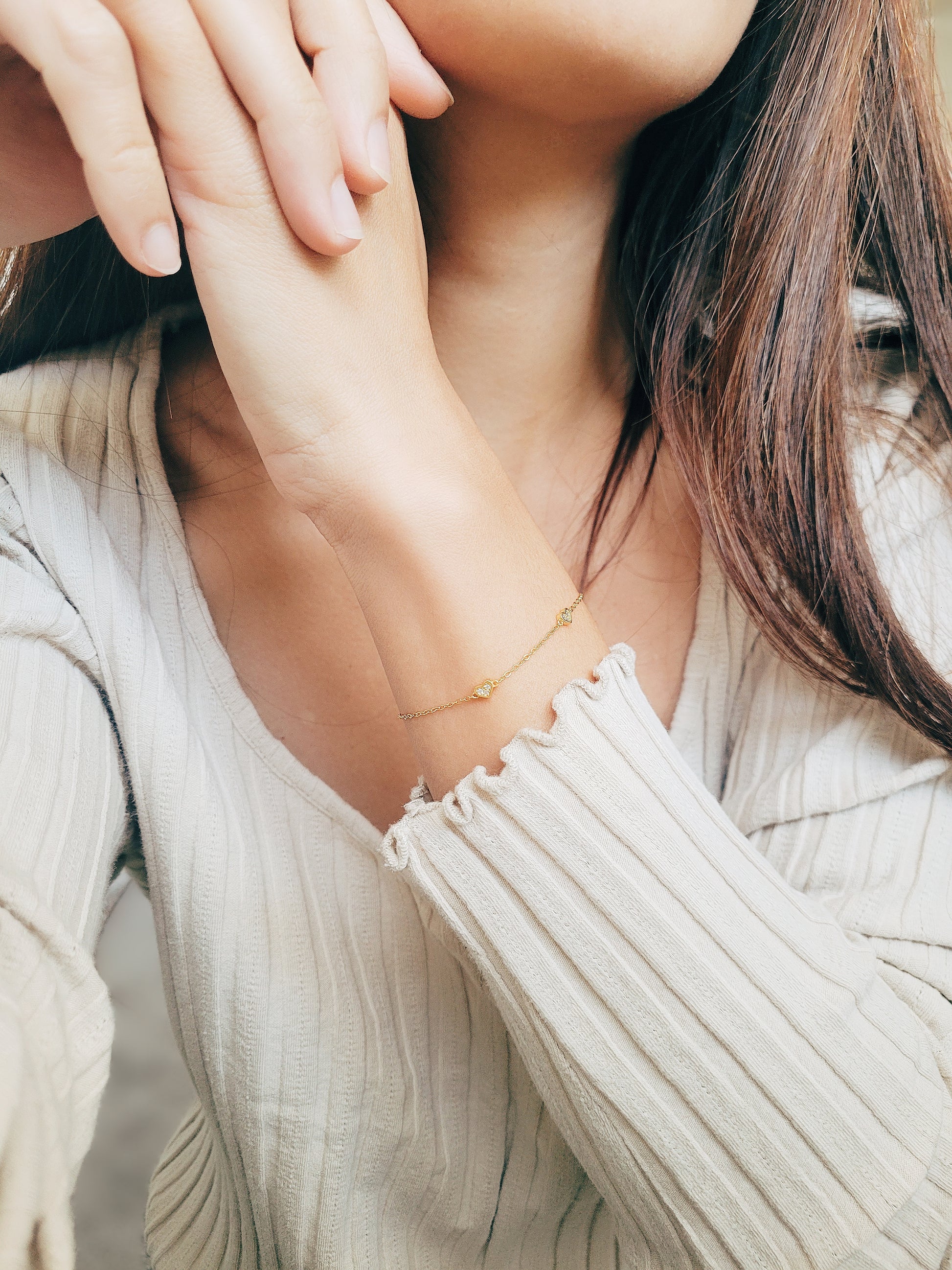 a woman wearing the mini heart bracelet in a calm posture