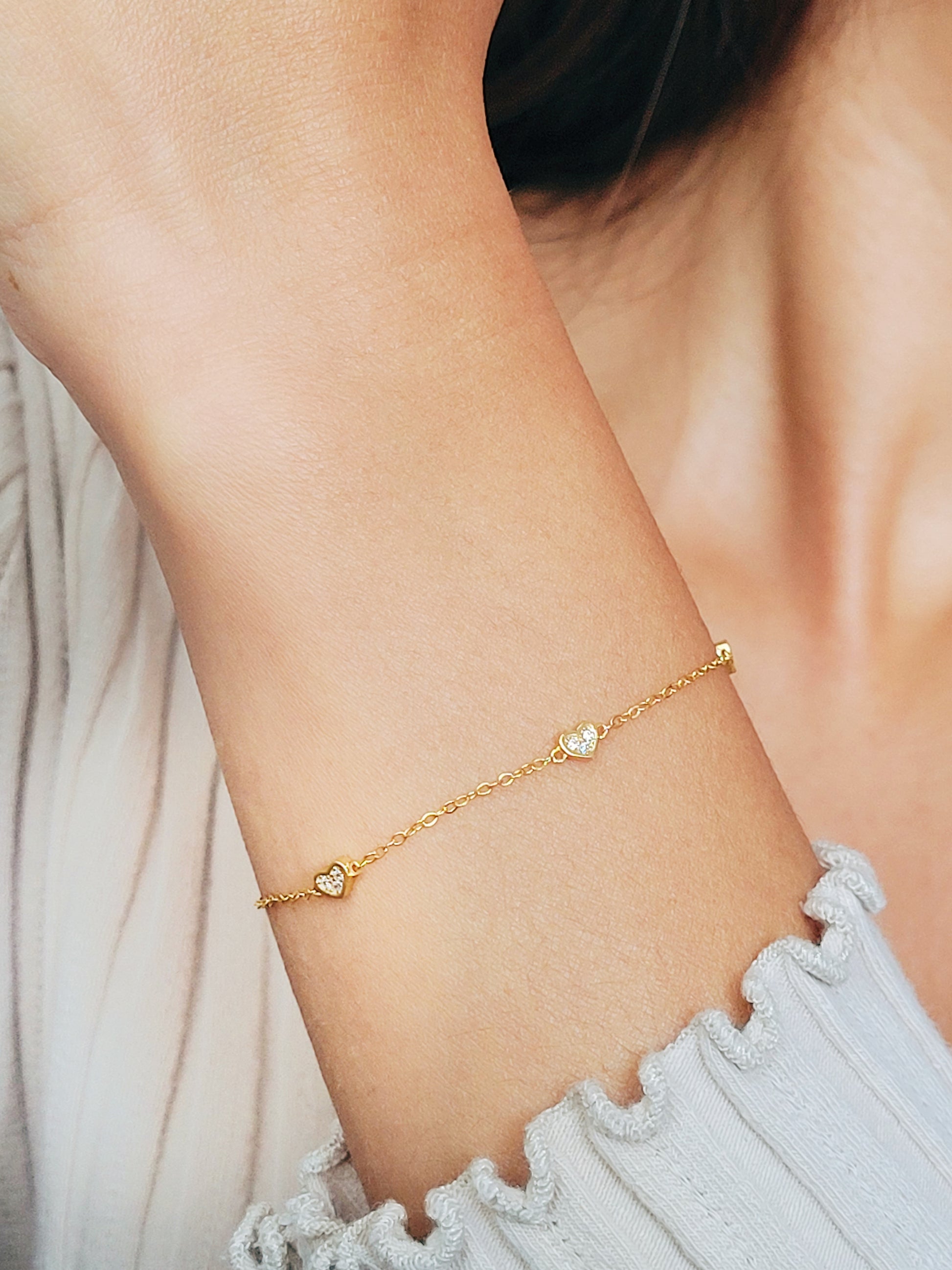 A close up on a women's waist wearing mini heart bracelet.