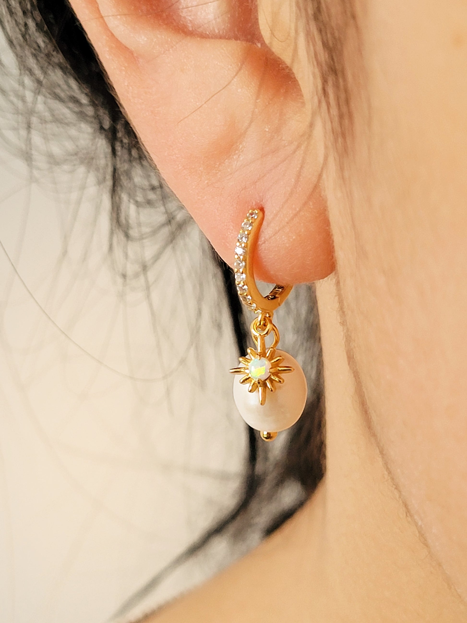 Woman wearing dainty freshwater pearl drop earring featuring a gold opal charm, crafted in gold plated sterling silver. Perfect bridal or everyday earrings with celestial charm and timeless sophistication. Birthday gift for her.