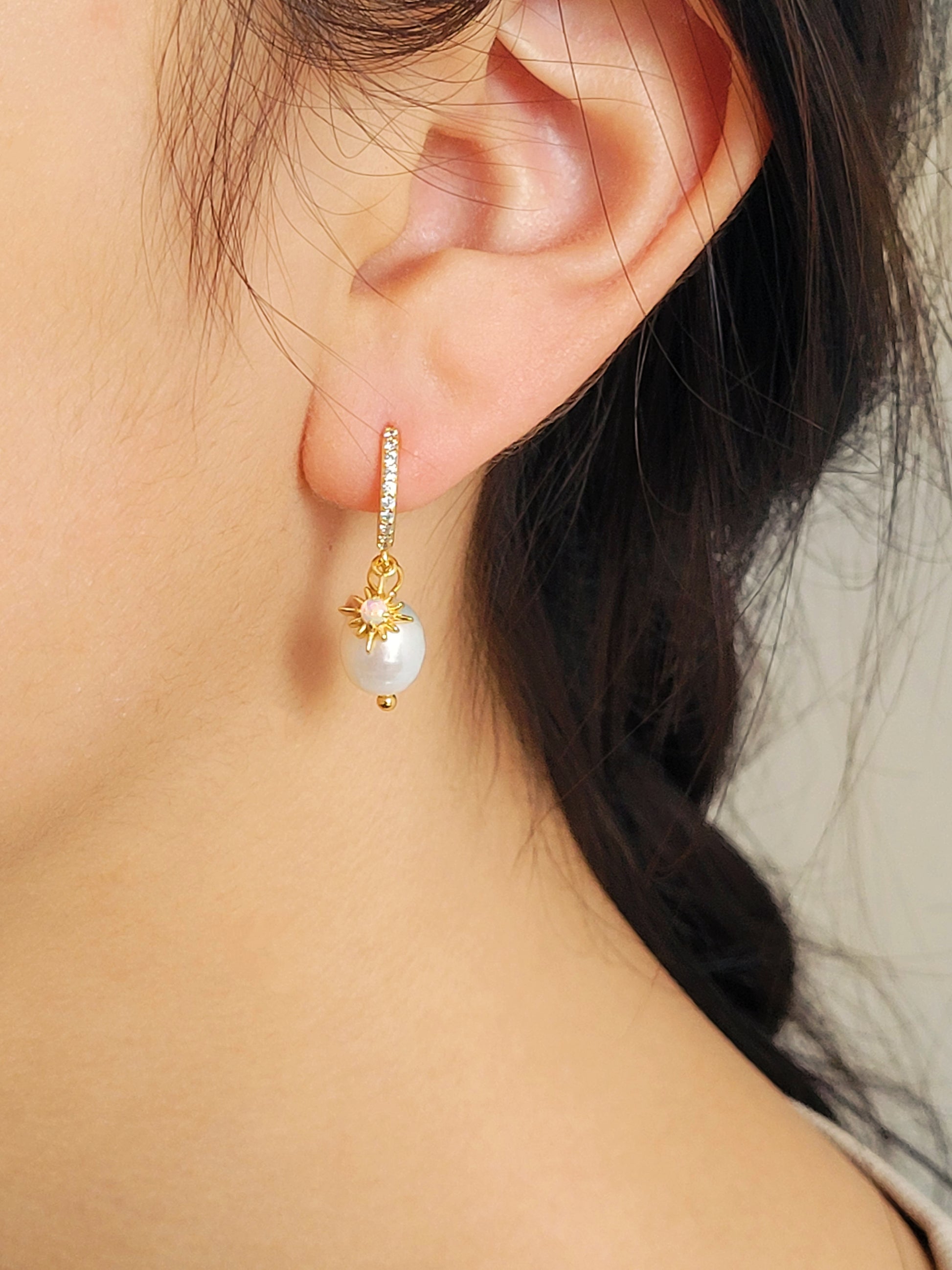 Woman wearing minimalist Opal huggie earrings featuring a freshwater pearl drop, crafted in gold plated sterling silver. Perfect bridal or everyday earrings with celestial charm and timeless sophistication. Birthday gift for her.
