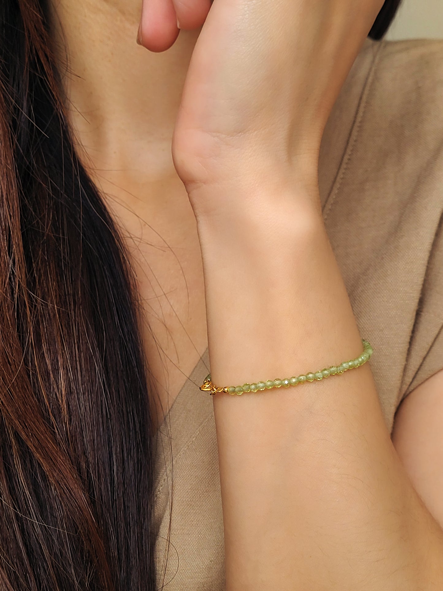 Woman wearing a dainty green peridot bracelet on her wrist