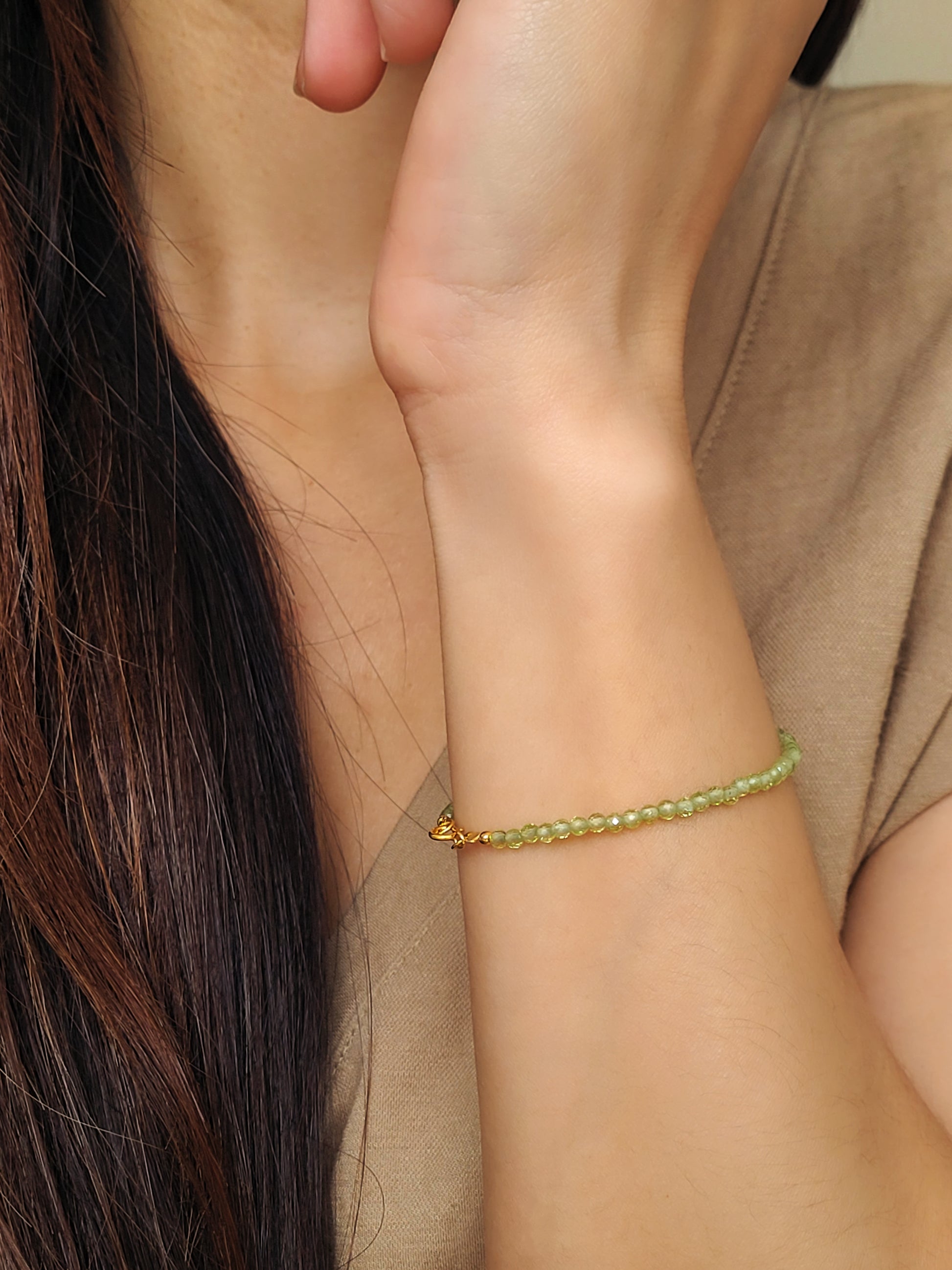 Woman wearing a dainty green peridot bracelet on her wrist