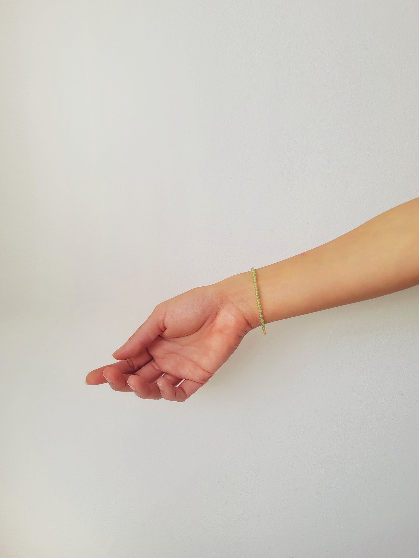 Woman wearing a dainty green peridot bracelet on her wrist
