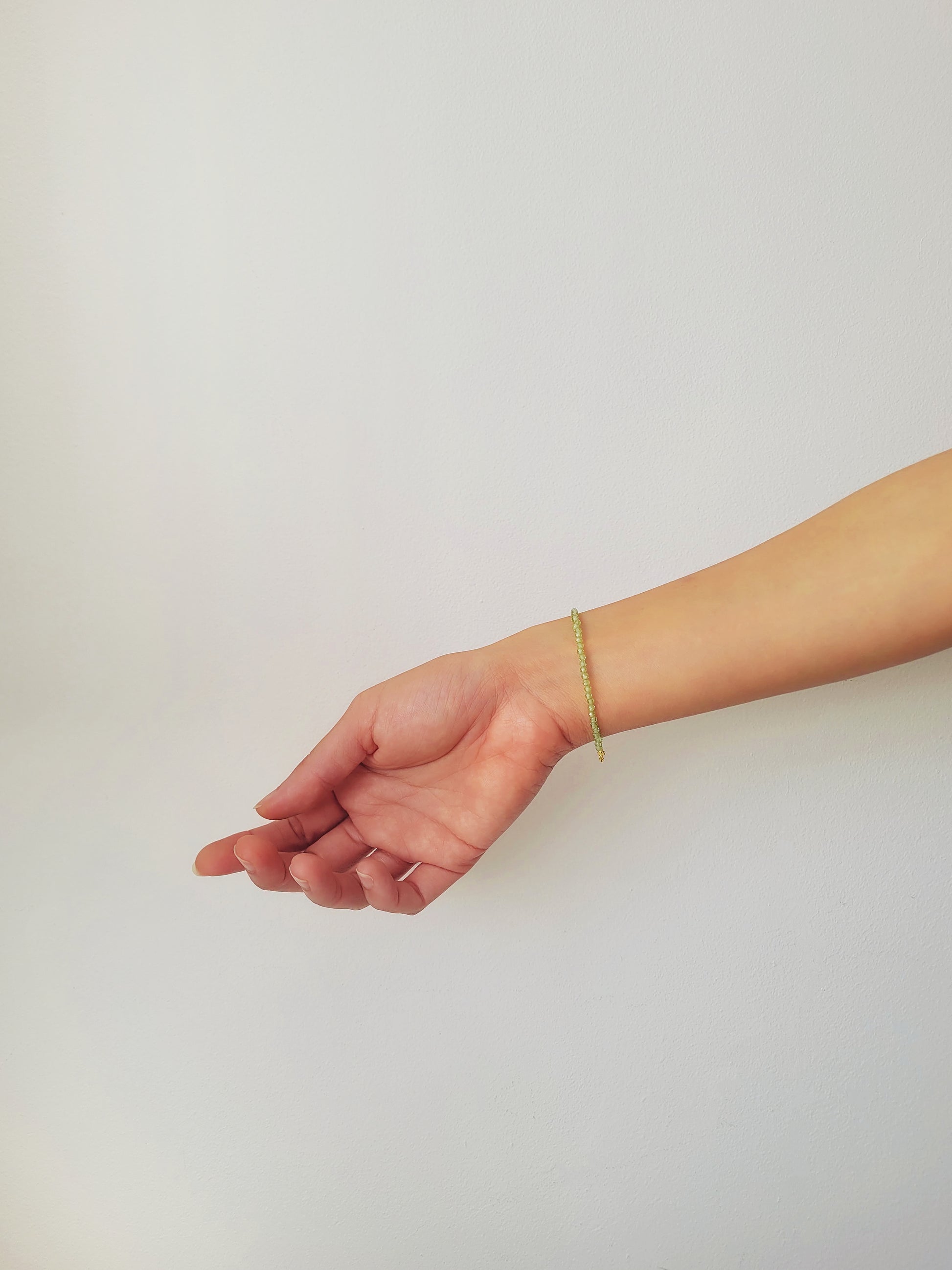 Woman wearing a dainty green peridot bracelet on her wrist