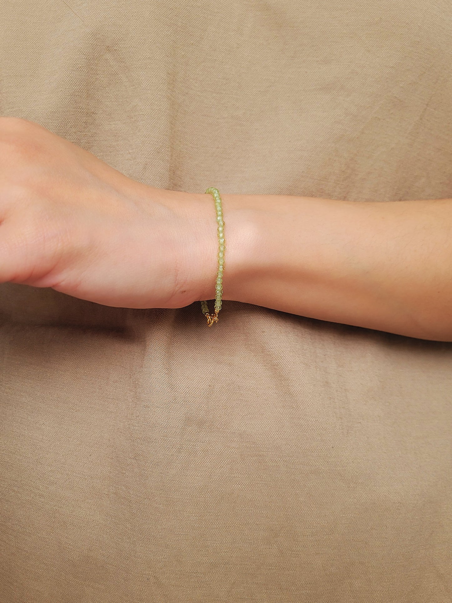 Woman wearing a dainty green peridot bracelet on her wrist