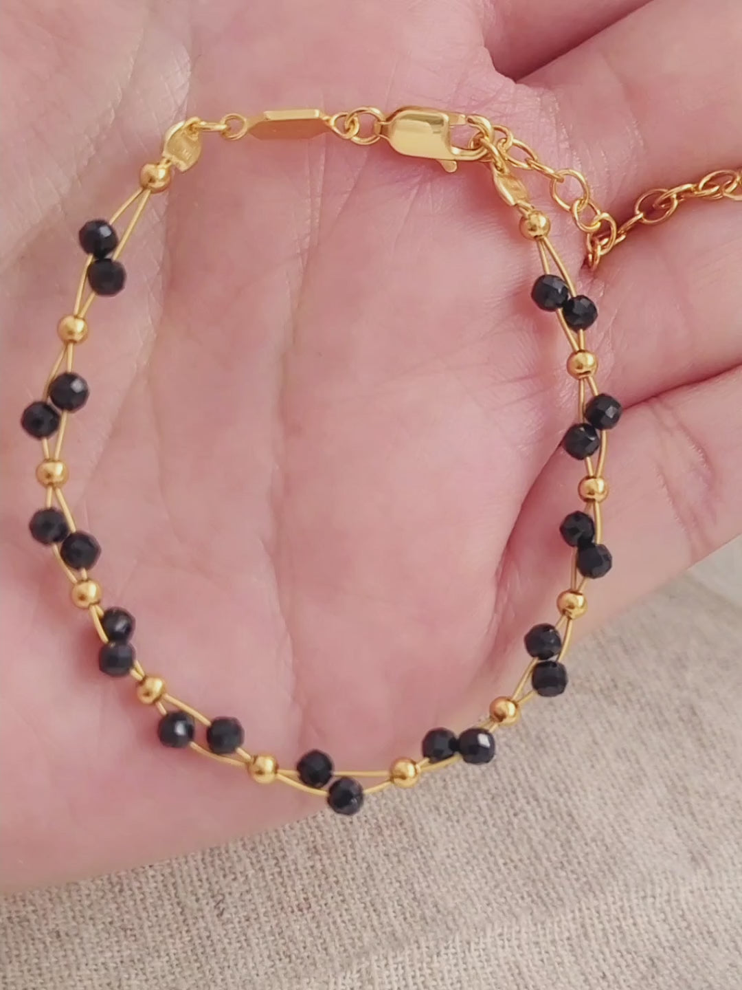 Close-up of a black spinel beaded bangle bracelet with 22k gold accents, styled for minimalist everyday wear. Handmade in natural gemstone and gold plated sterling silver premium materials, perfect gift for anniversary, birthday or self care.