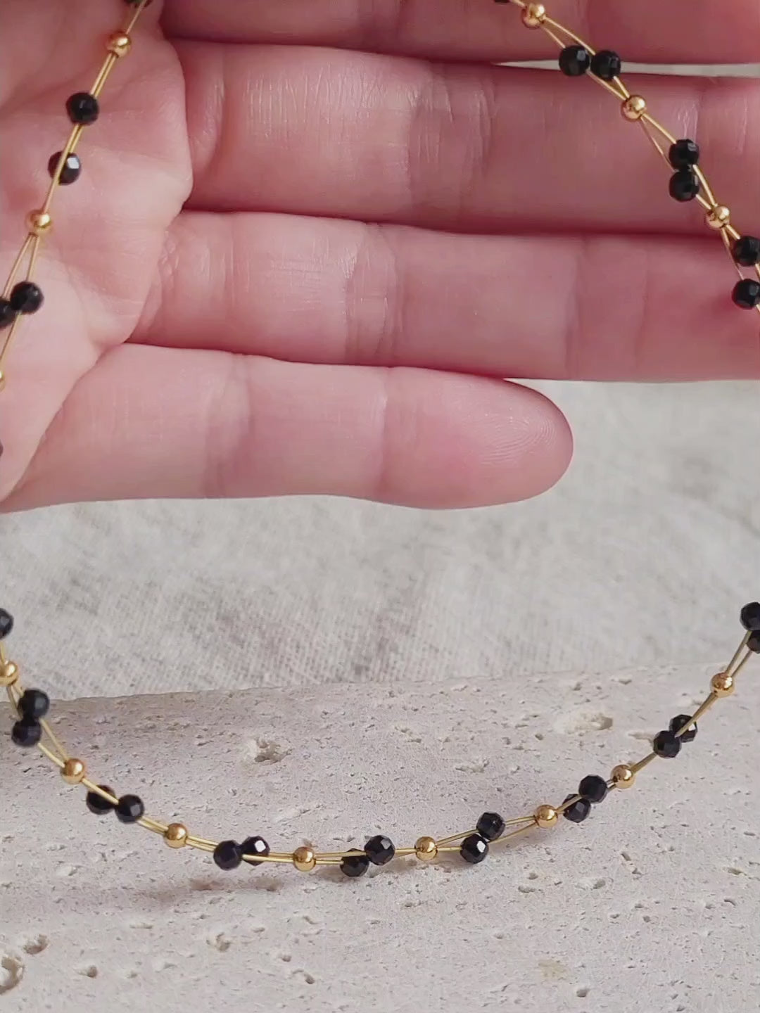 Close-up of a woman wearing a black spinel beaded choker necklace with 22k gold accents, styled for minimalist everyday wear. Handmade in natural gemstone and gold plated sterling silver premium materials, perfect gift for anniversary, birthday or self care.