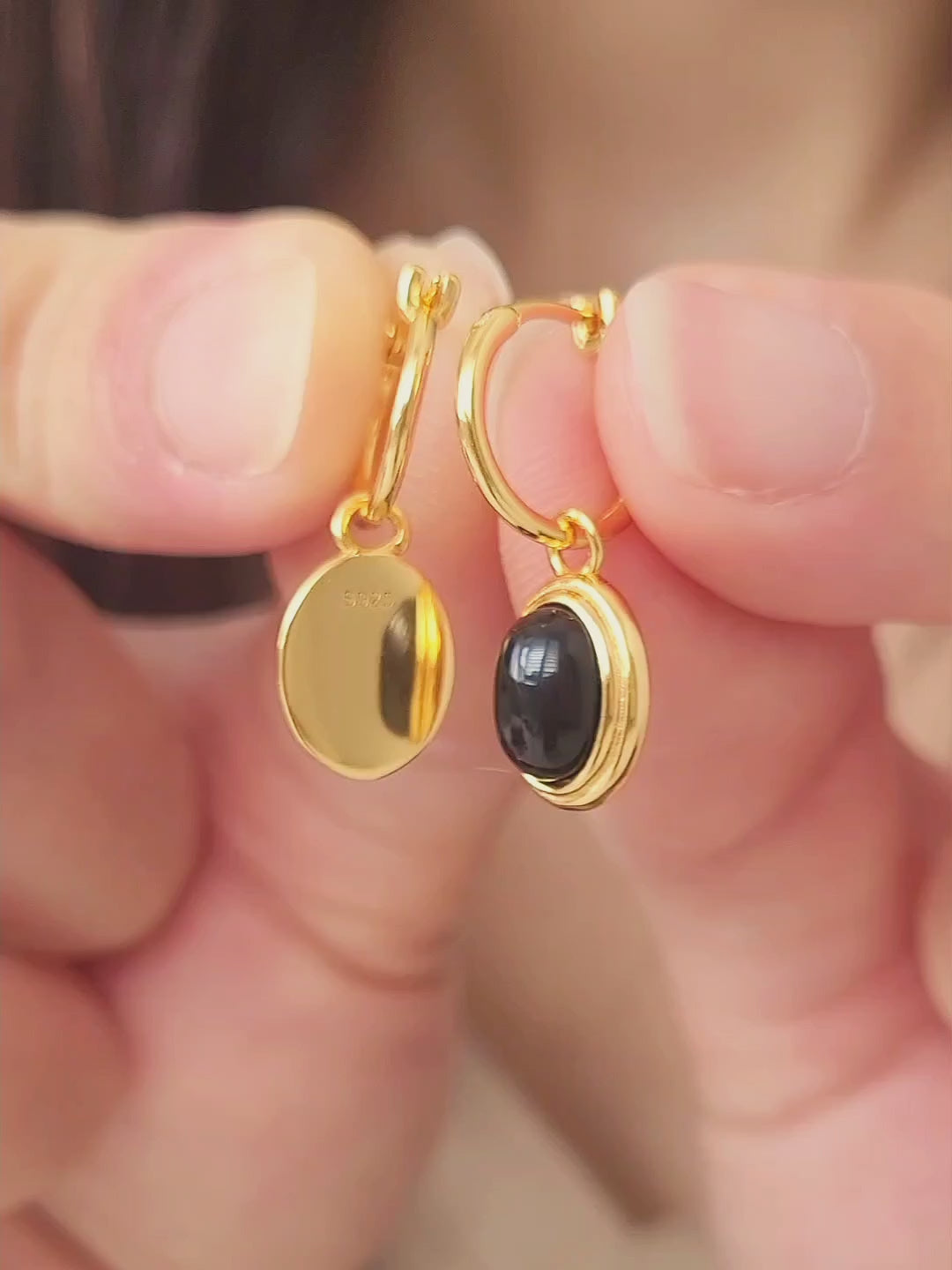 Close-up of gold vermeil dangle earrings with an oval black onyx gemstone, minimalist and elegant style