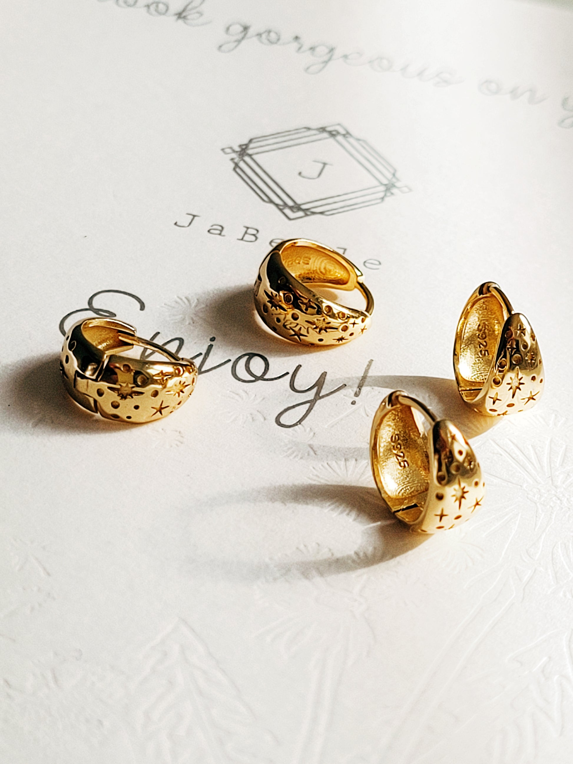 Gold star huggie earrings displayed on a white surface
