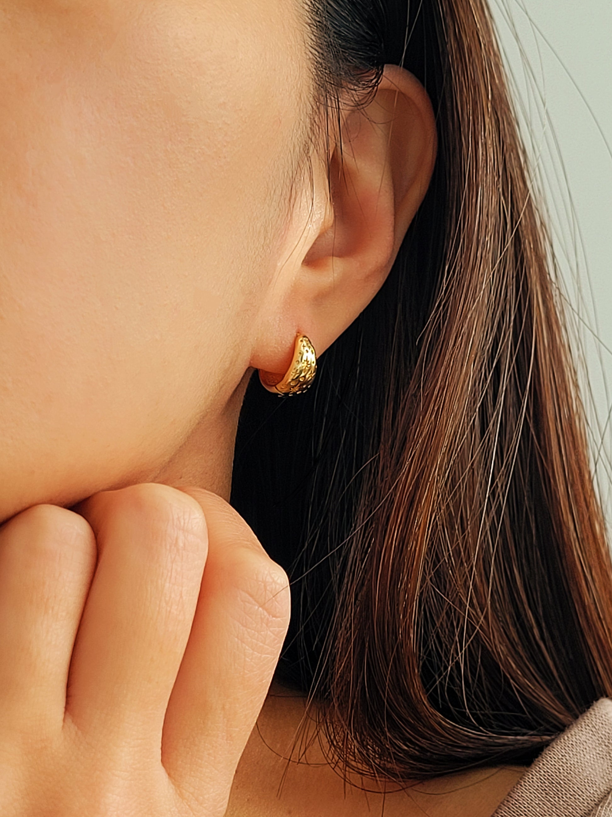 Close-up of a girl wearing a gold earring with stars engraved