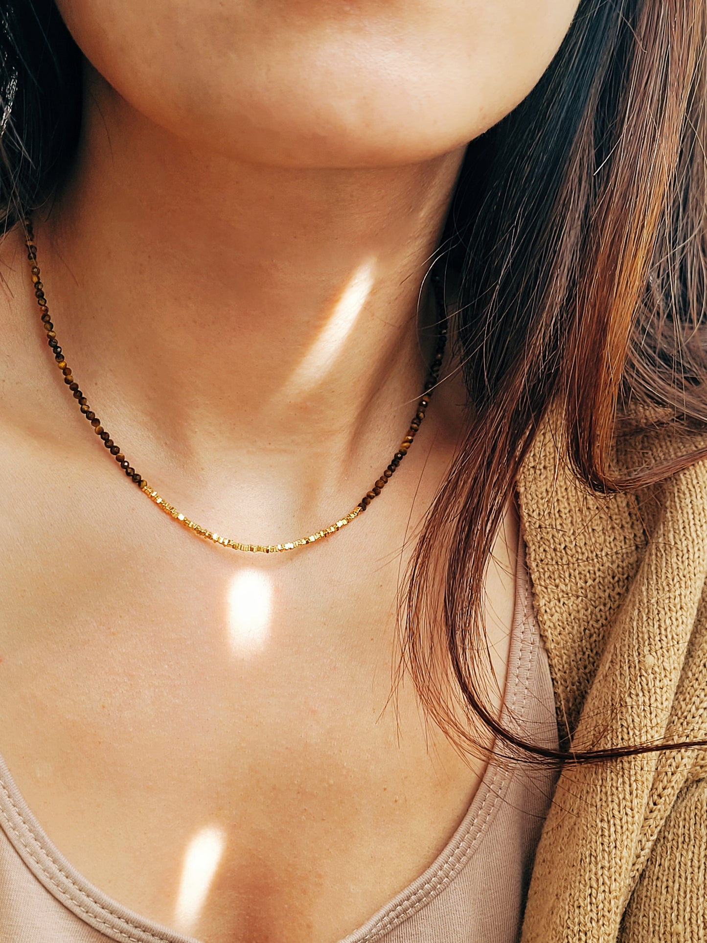 Close-up of woman wearing Tiger’s Eye gemstone choker necklace with 22K gold vermeil nugget beads in natural sunlight