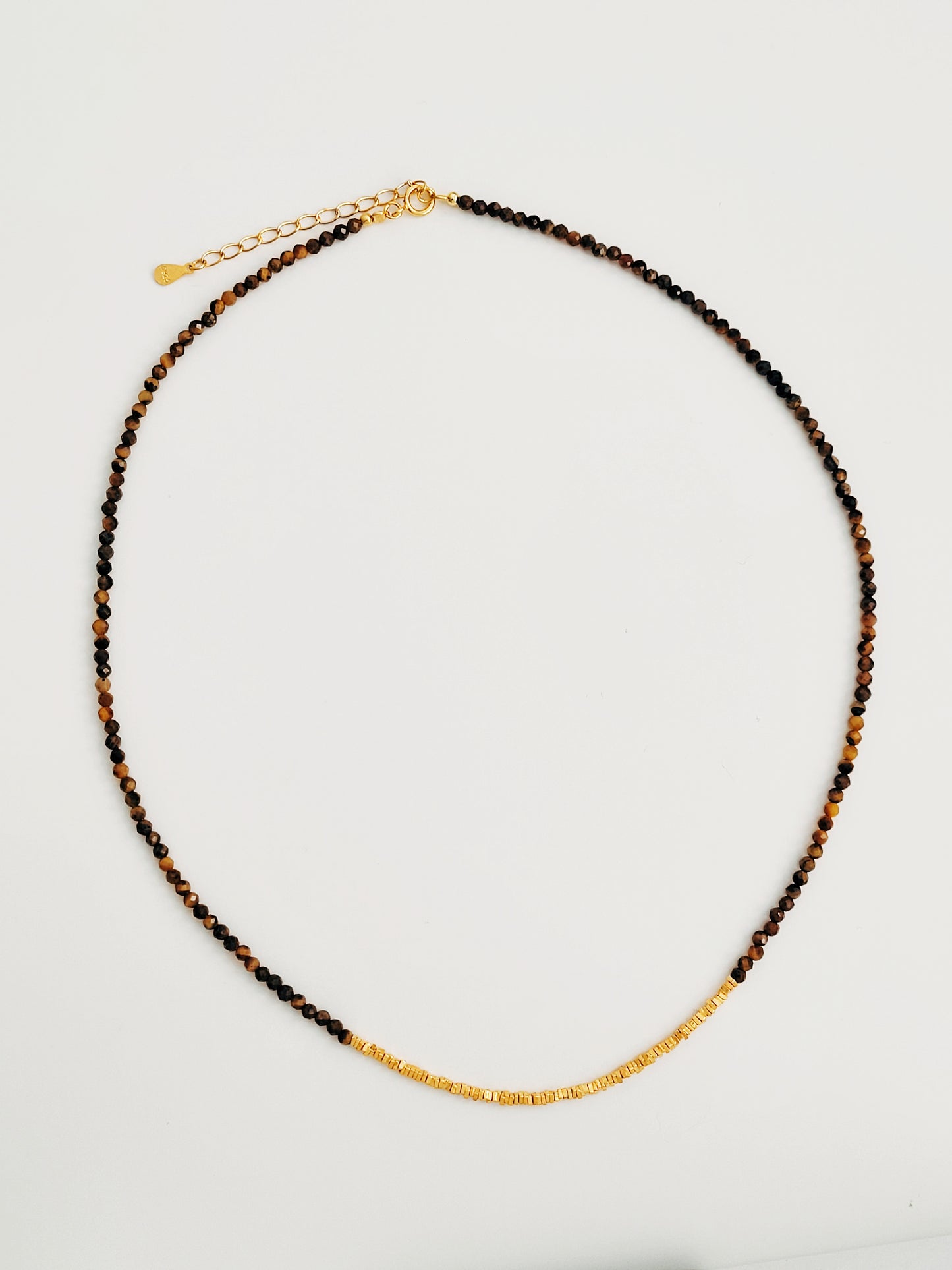 Close-up of a Tiger’s Eye gemstone choker necklace with 22K gold vermeil nugget beads on white surface