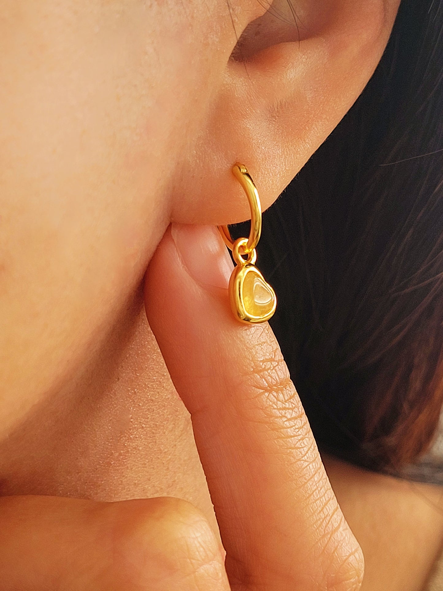 Heart huggie hoop earring worn on an ear, earrings are crafted in natural quartz gemstone and 18k gold plated sterling silver