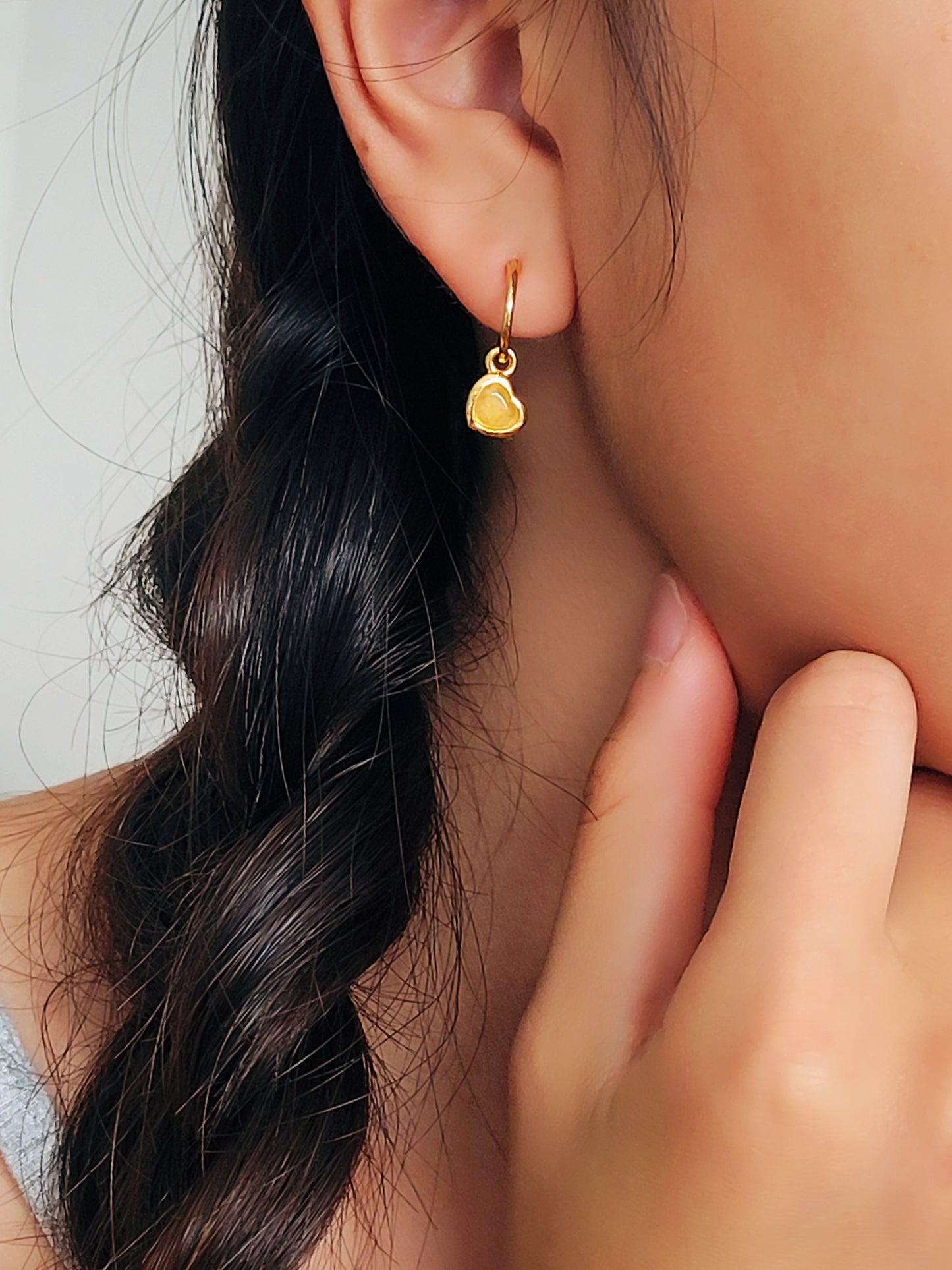 Woman wearing cute and dainty yellow heart dangle gold earrings, crafted in natural quartz crystal gemstone. Perfect anniversary gift for girl.