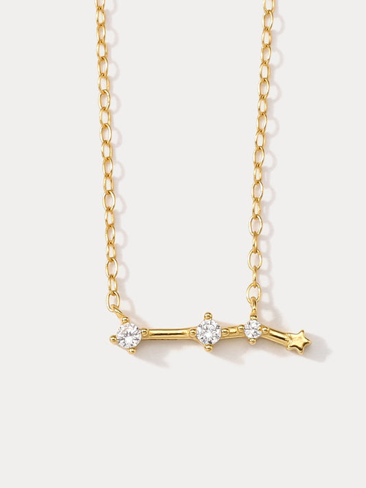 A dainty gold necklace with a pendant featuring a stylized Aries zodiac constellation sign with sparkling zircons.