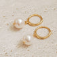 Close-up of gold hoop earrings with dangling pearls, highlighting their polished and timeless craftsmanship.