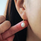Close-up of a woman wearing a gold-plated pearl drop earring, showcasing its elegant and minimalist design.