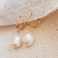 Minimalist gold and pearl drop earrings displayed against a soft beige backdrop for a refined look.